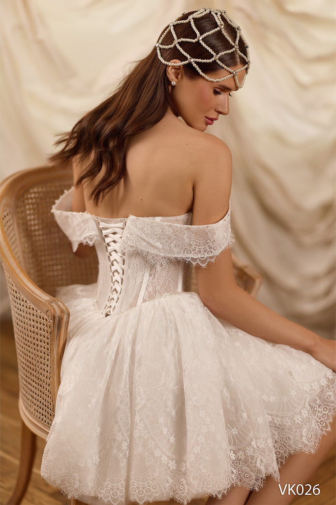 Off-the-shoulder bridal mini dress with sheer corset bodice, pearl draping, lace detailing, voluminous skirt, and lace-up back
