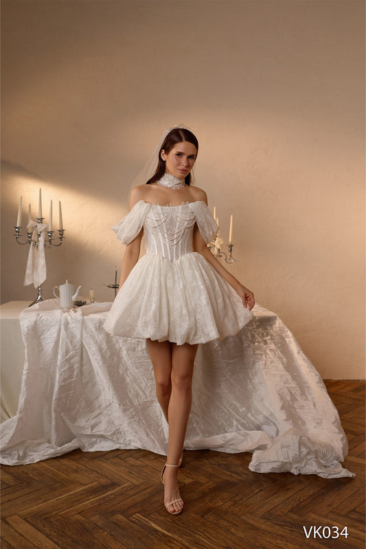 Short bridal dress with pearl-draped corset bodice, off-the-shoulder sleeves, lace detailing, and bubble skirt