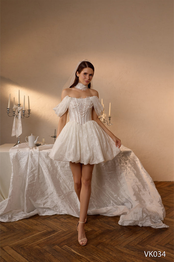 Short bridal dress with pearl-draped corset bodice, off-the-shoulder sleeves, lace detailing, and bubble skirt