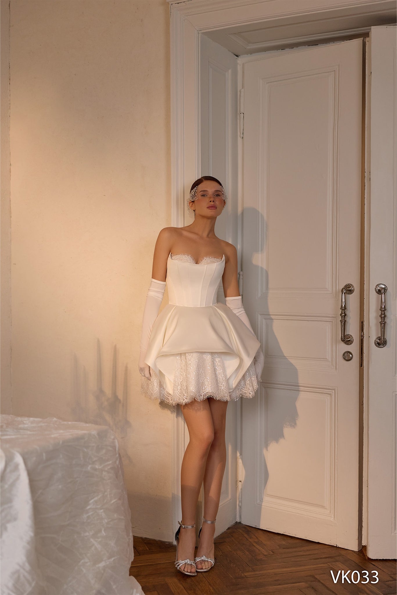 Strapless bridal mini dress with structured overskirt, corset bodice, and sparkling lace detailing