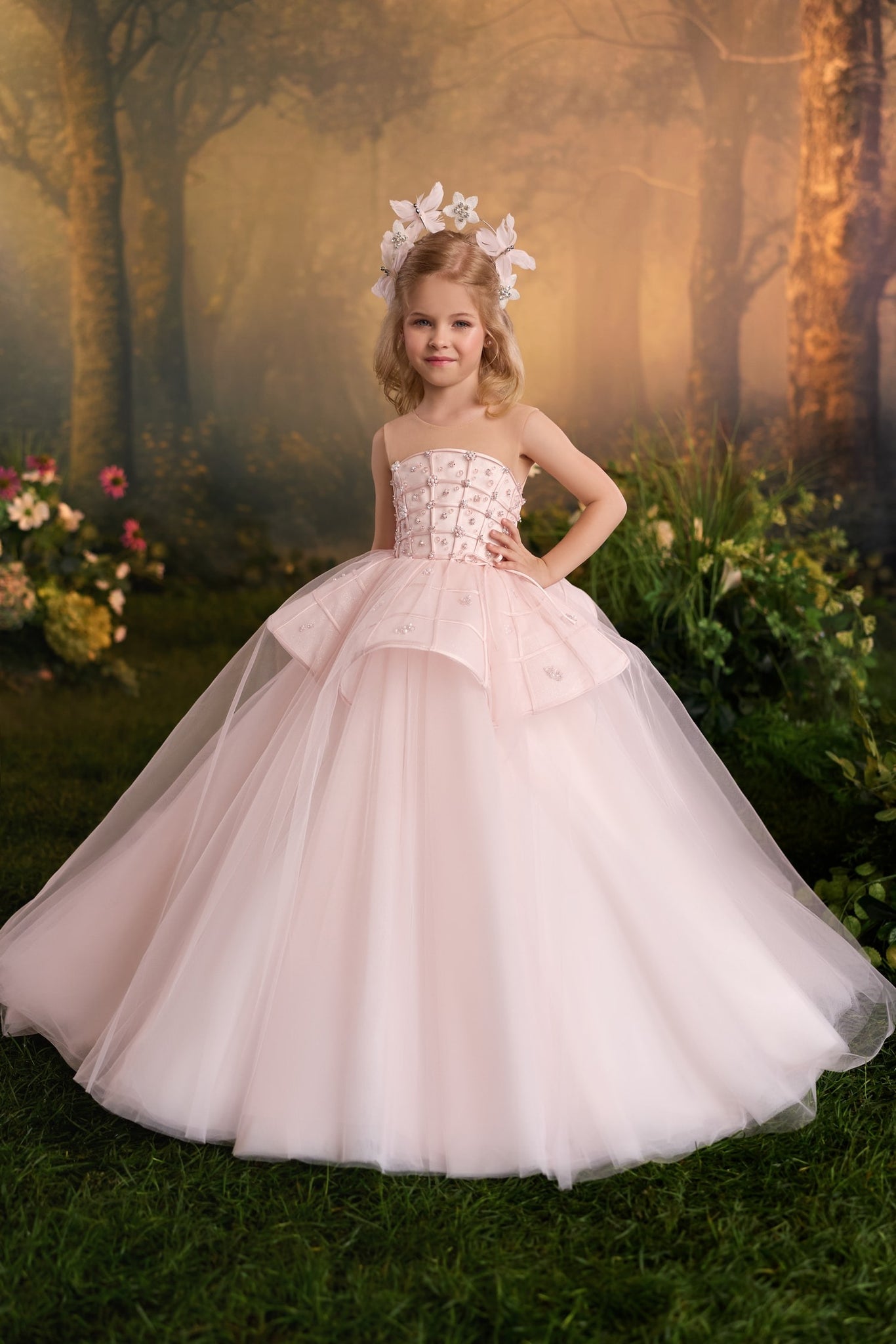 Girl wearing a pale pink ball gown with a floral headpiece in a forest setting