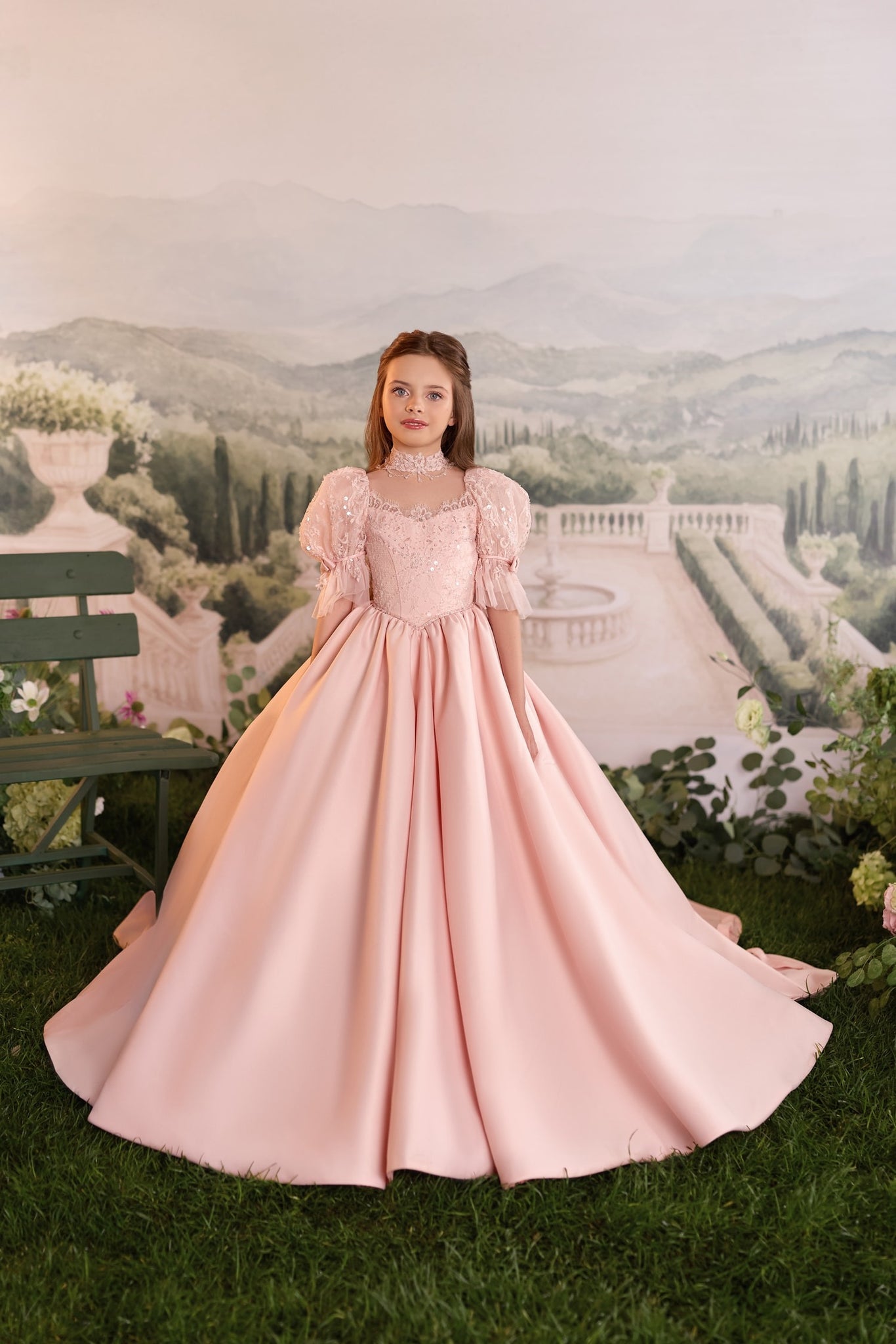 Girl wearing a pink ball gown with puff sleeves and lace detail