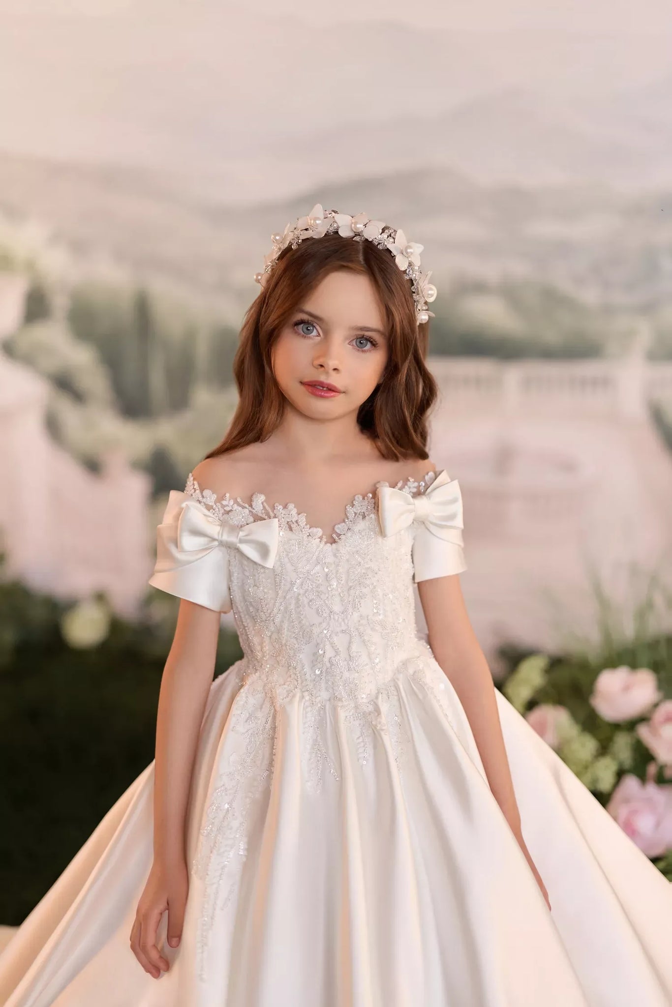 Girl wearing a white off the shoulder dress with bow details and a floral headpiece