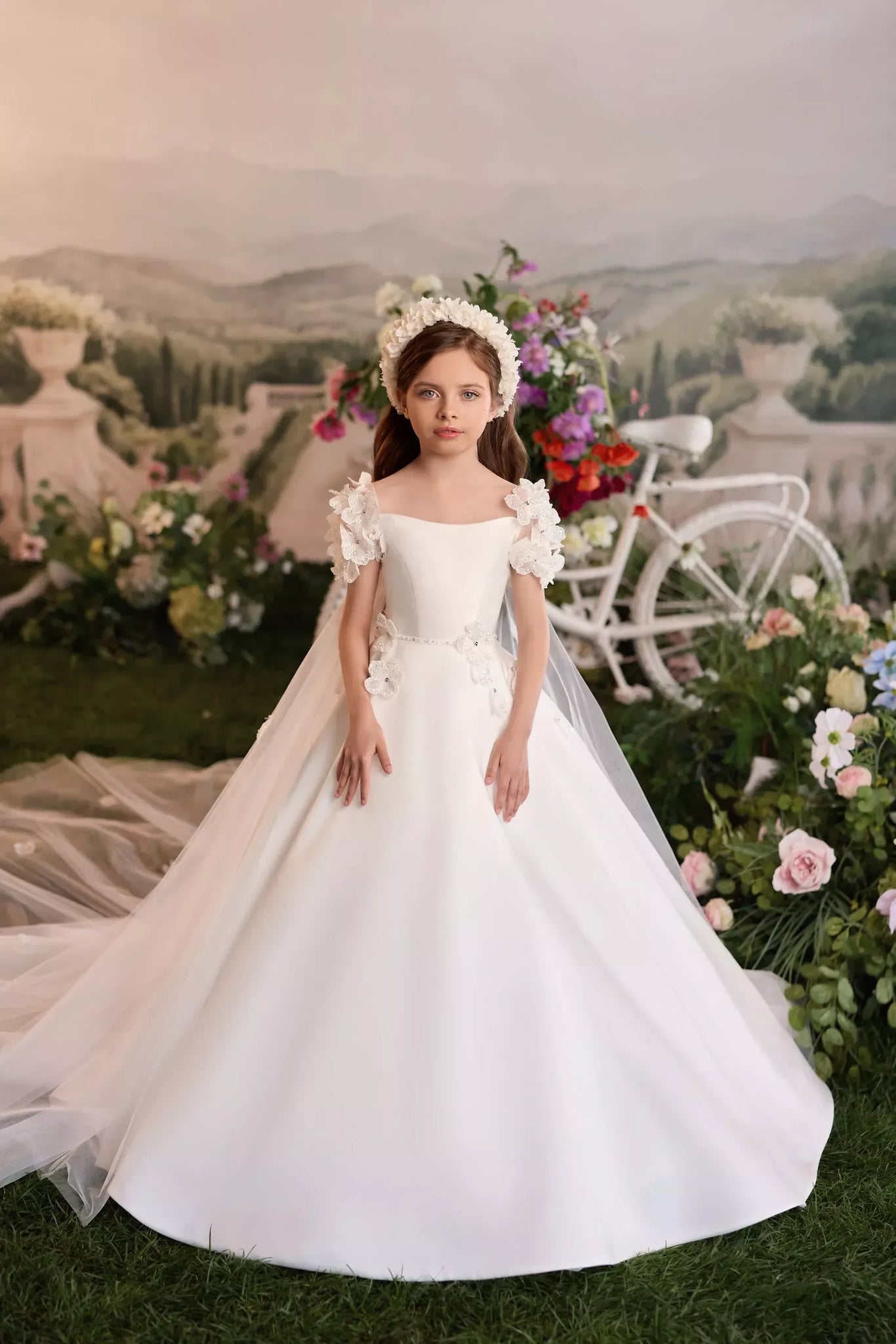 Girl wearing a white floor length dress with floral sleeves and a flower crown
