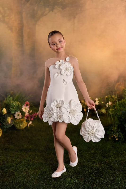 Girl wearing a white dress with floral appliques and holding a matching flower shaped handbag