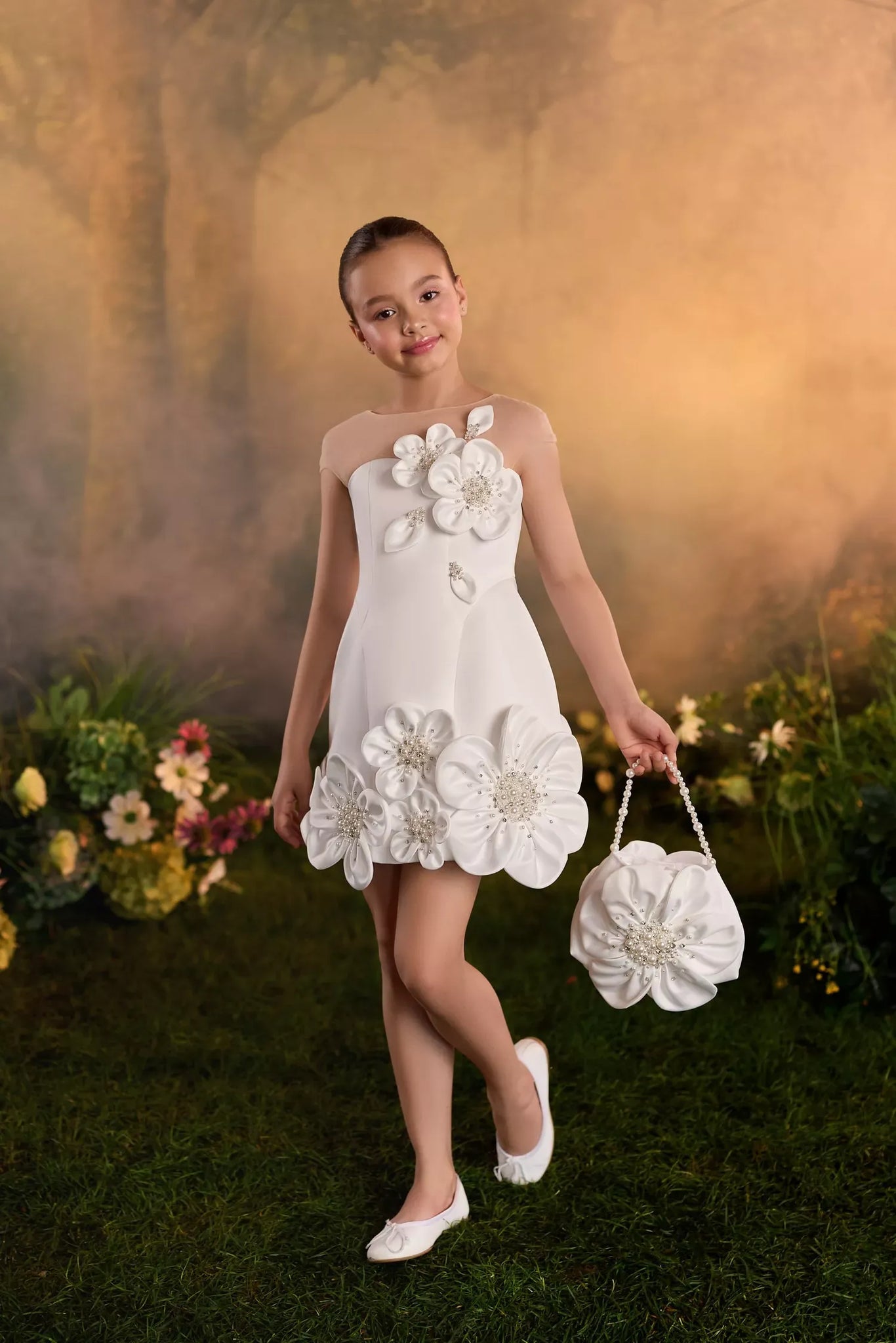 Girl wearing a white dress with floral appliques and holding a matching flower shaped handbag