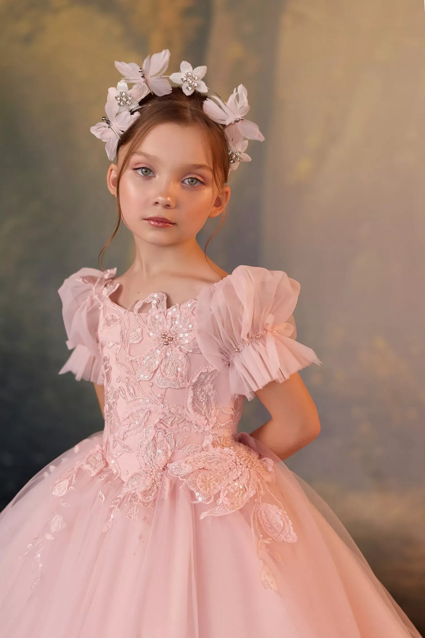 Girl wearing a pink tulle dress with floral embroidery and a matching flower headband