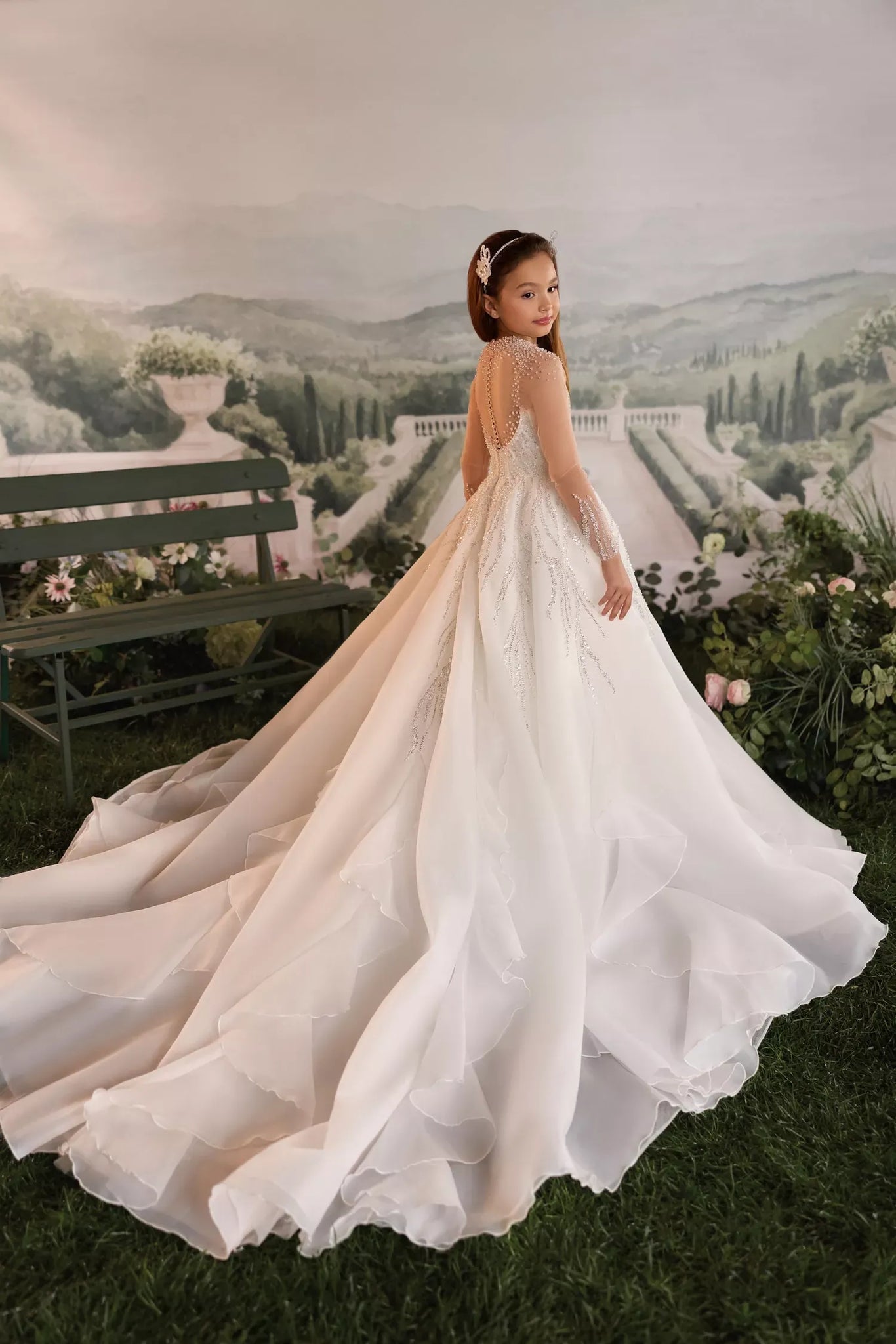 Girl wearing a white long sleeve ball gown with a beaded bodice and a layered tulle skirt