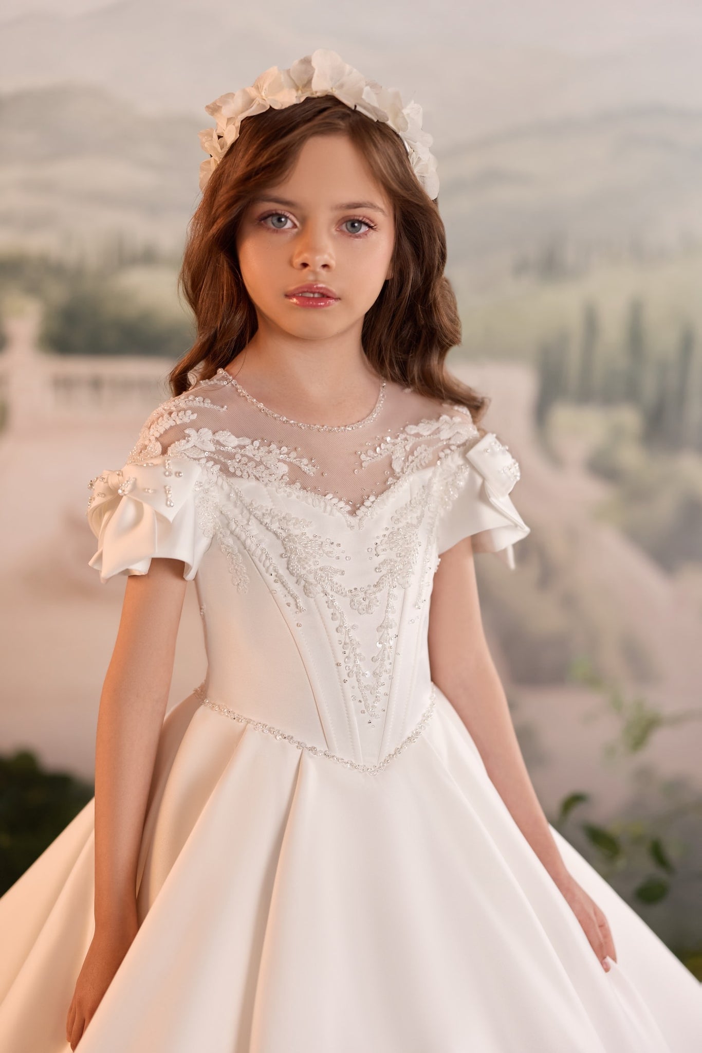Girl wearing a white communion dress with beaded bodice and floral headpiece