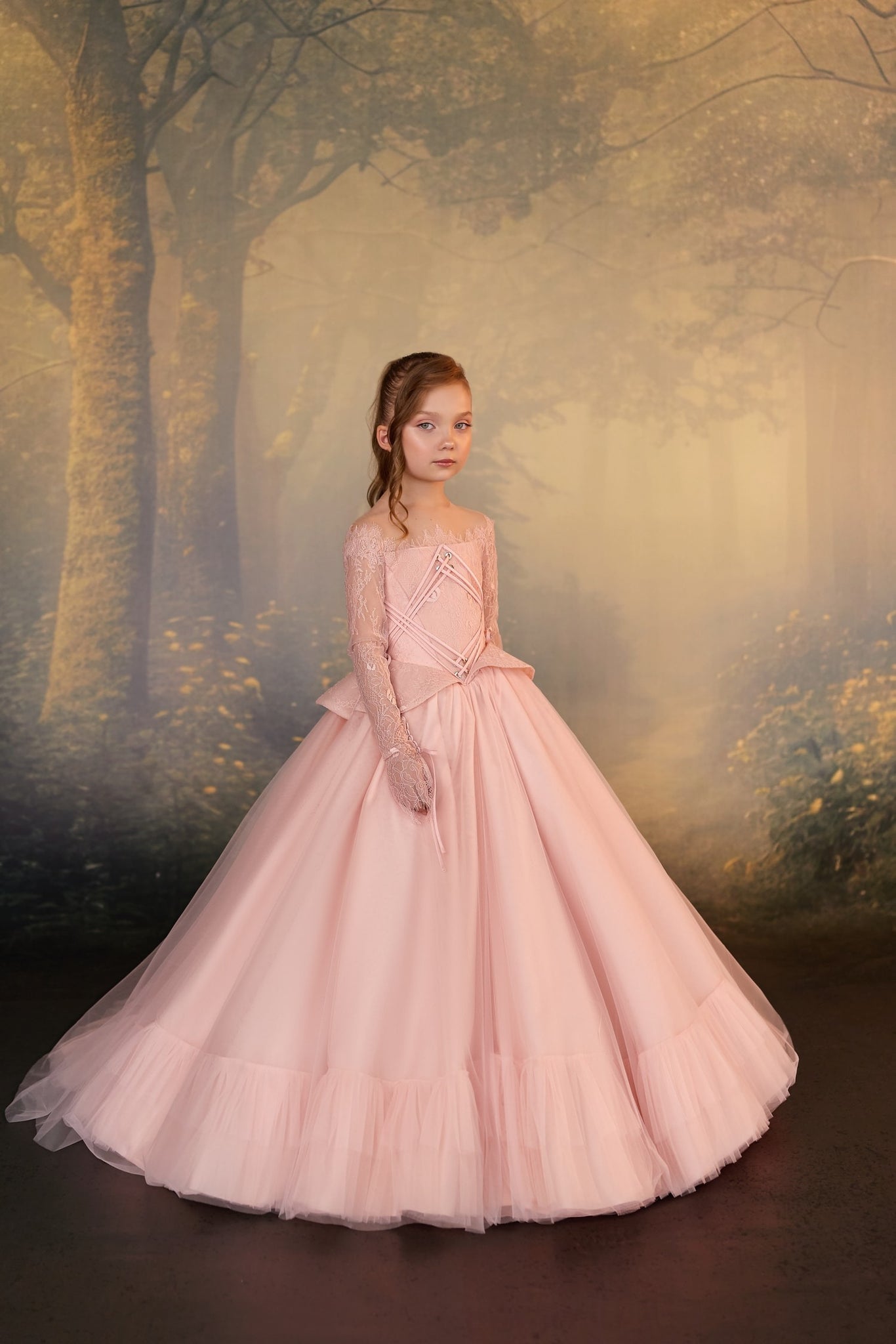 Girl wearing a pink lace ball gown with long sleeves and a full tulle skirt | Girls Formal Dress