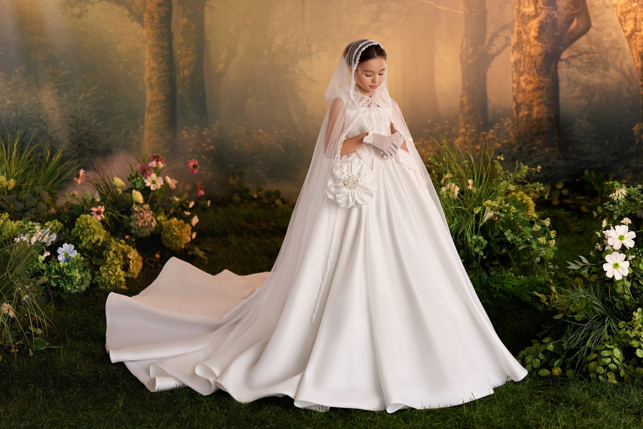 Girl wearing an embellished ball gown with a sheer cape and gloves in a garden setting | Girls Formal Dress