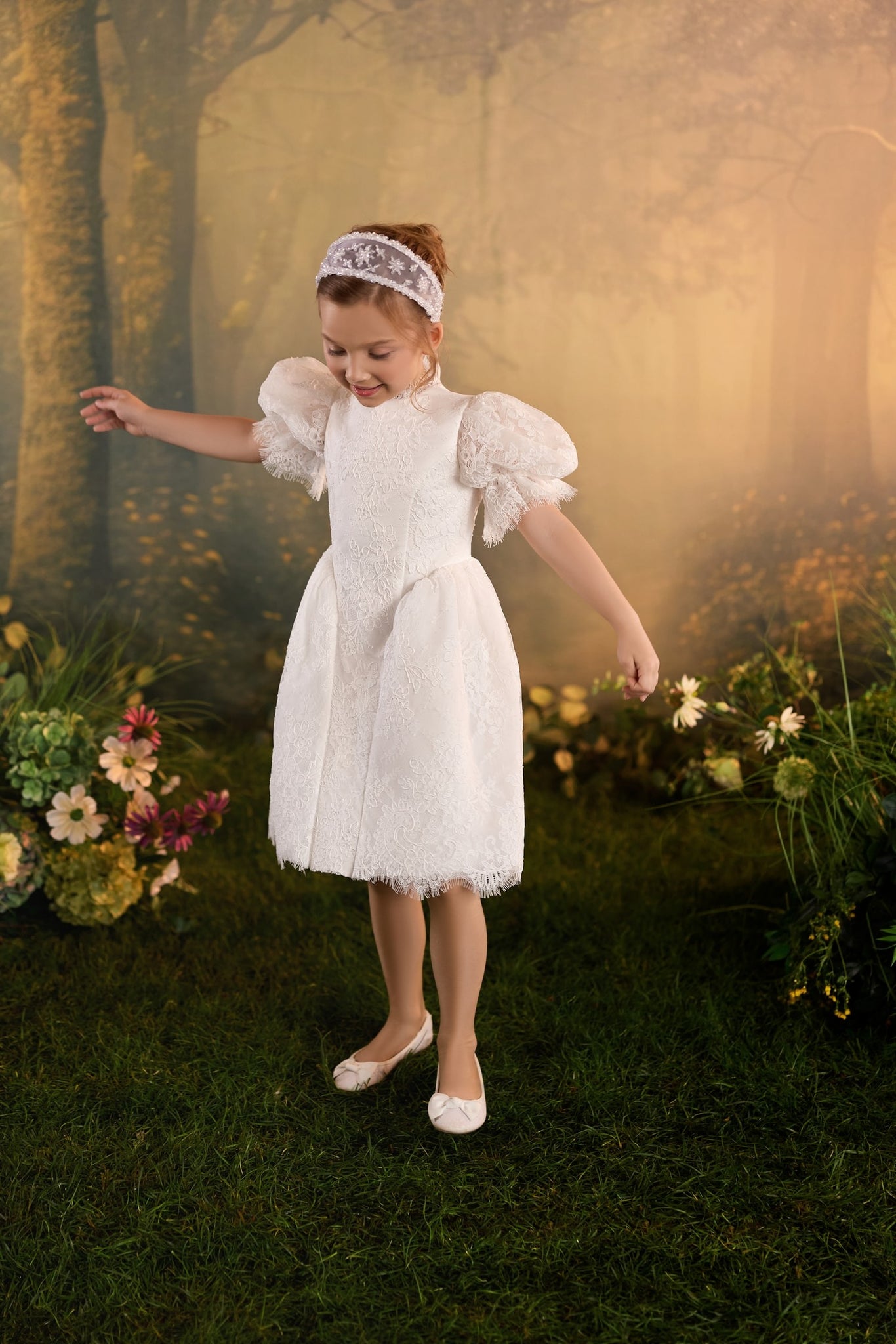 Girl wearing a white lace dress and headband standing in a garden | Girls Formal Dress