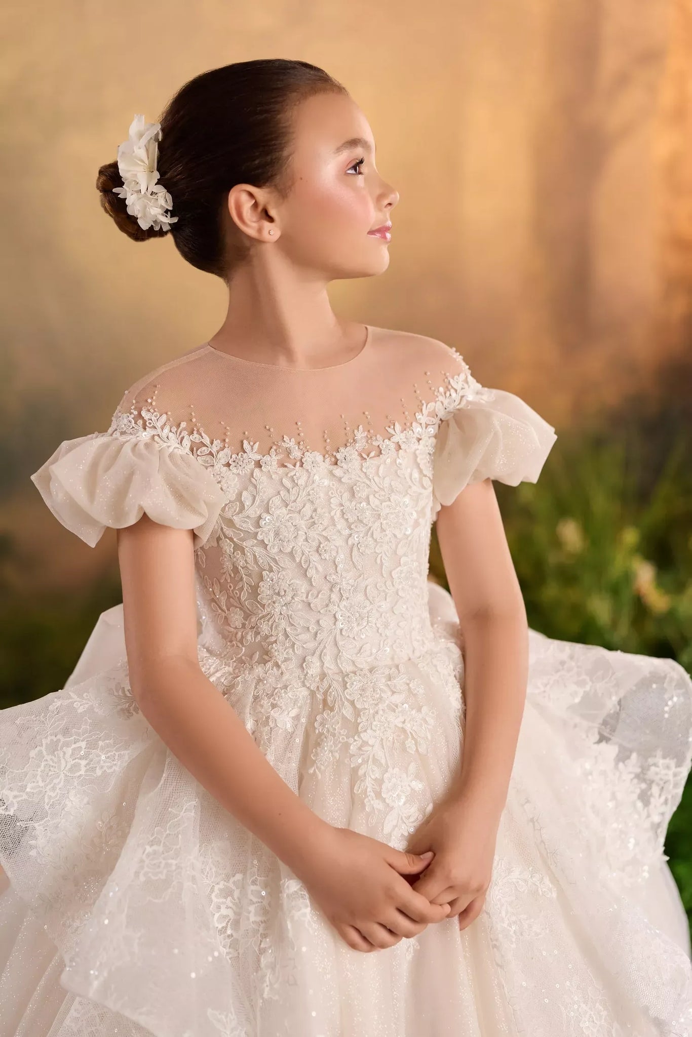 Girl wearing a white lace dress with puff sleeves and floral hair accessory