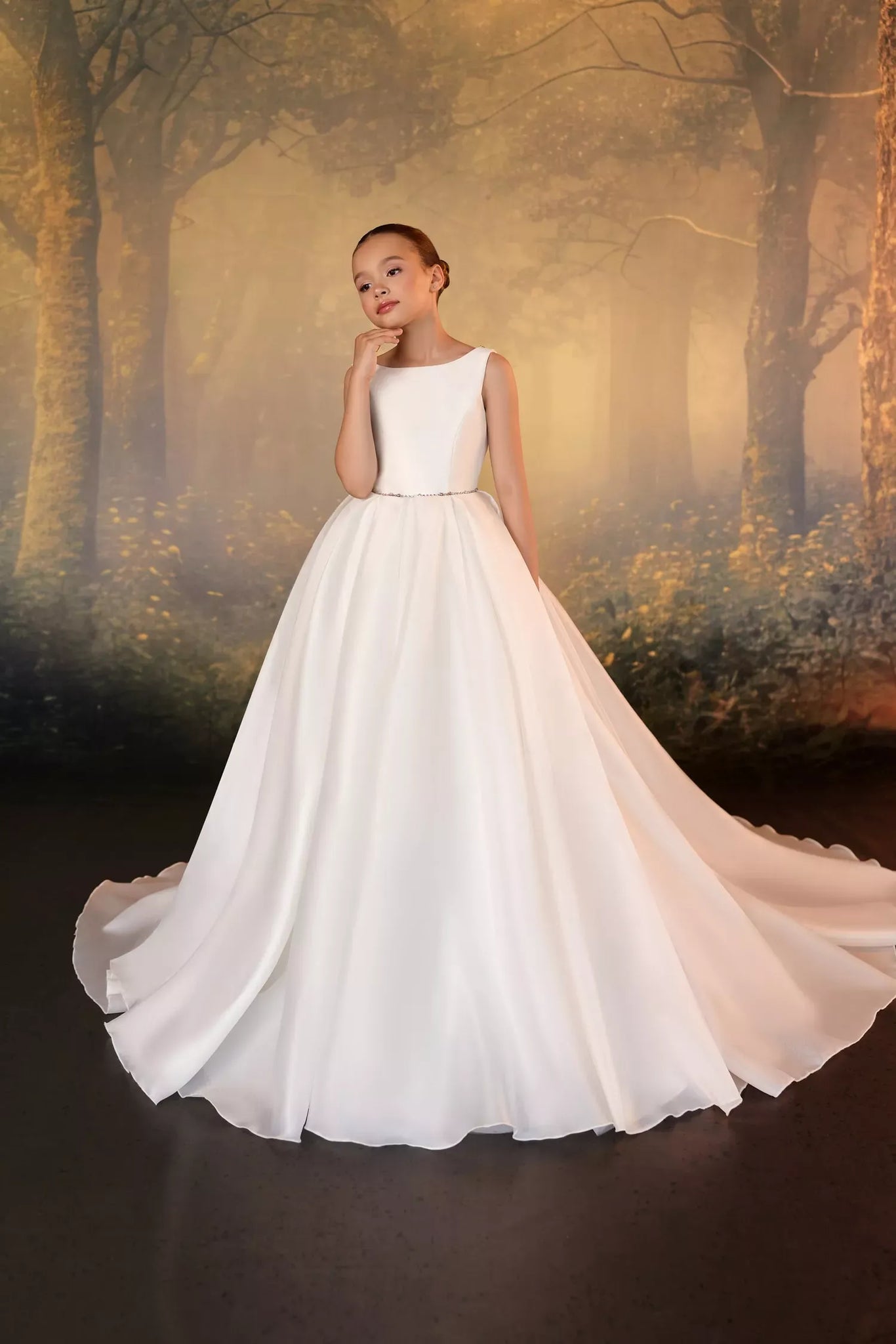 Girl wearing a white sleeveless ball gown with a beaded waistline against a forest backdrop | Girls Formal Dress