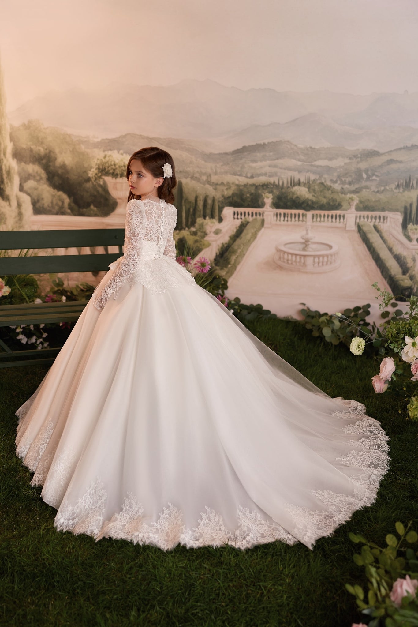Girl wearing a white lace long sleeve ball gown with a full skirt and train