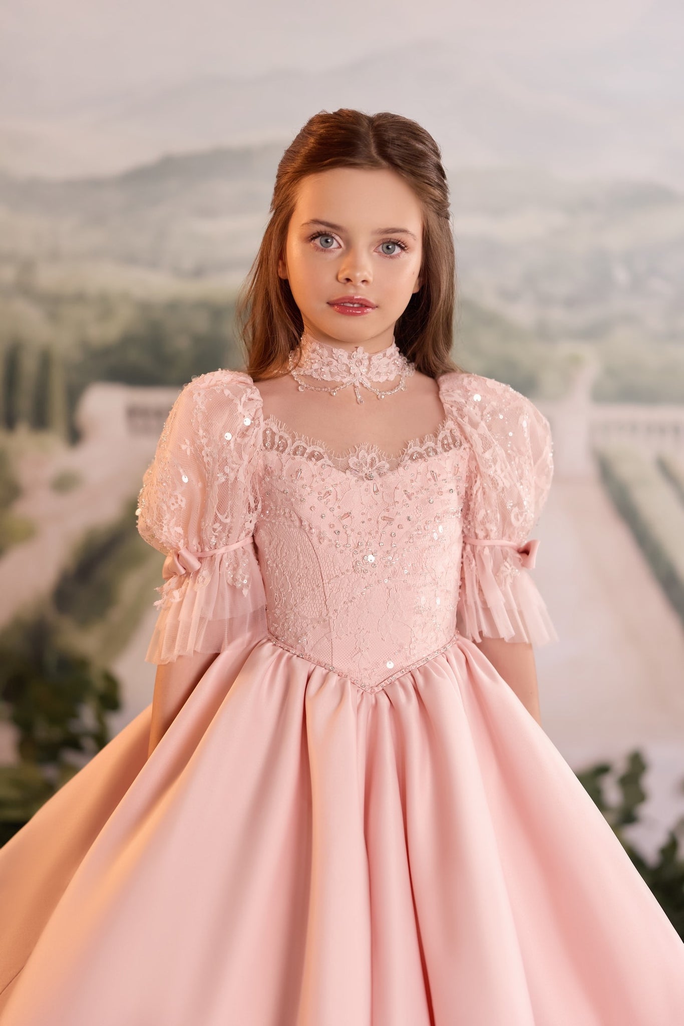 Girl wearing a pink lace ball gown with puff sleeves and a high neck choker
