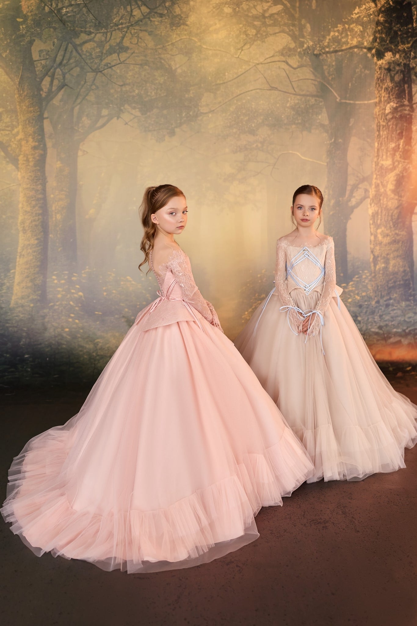 Two girls wearing long formal ball gowns standing in front of a forest backdrop | Girls Formal Dress