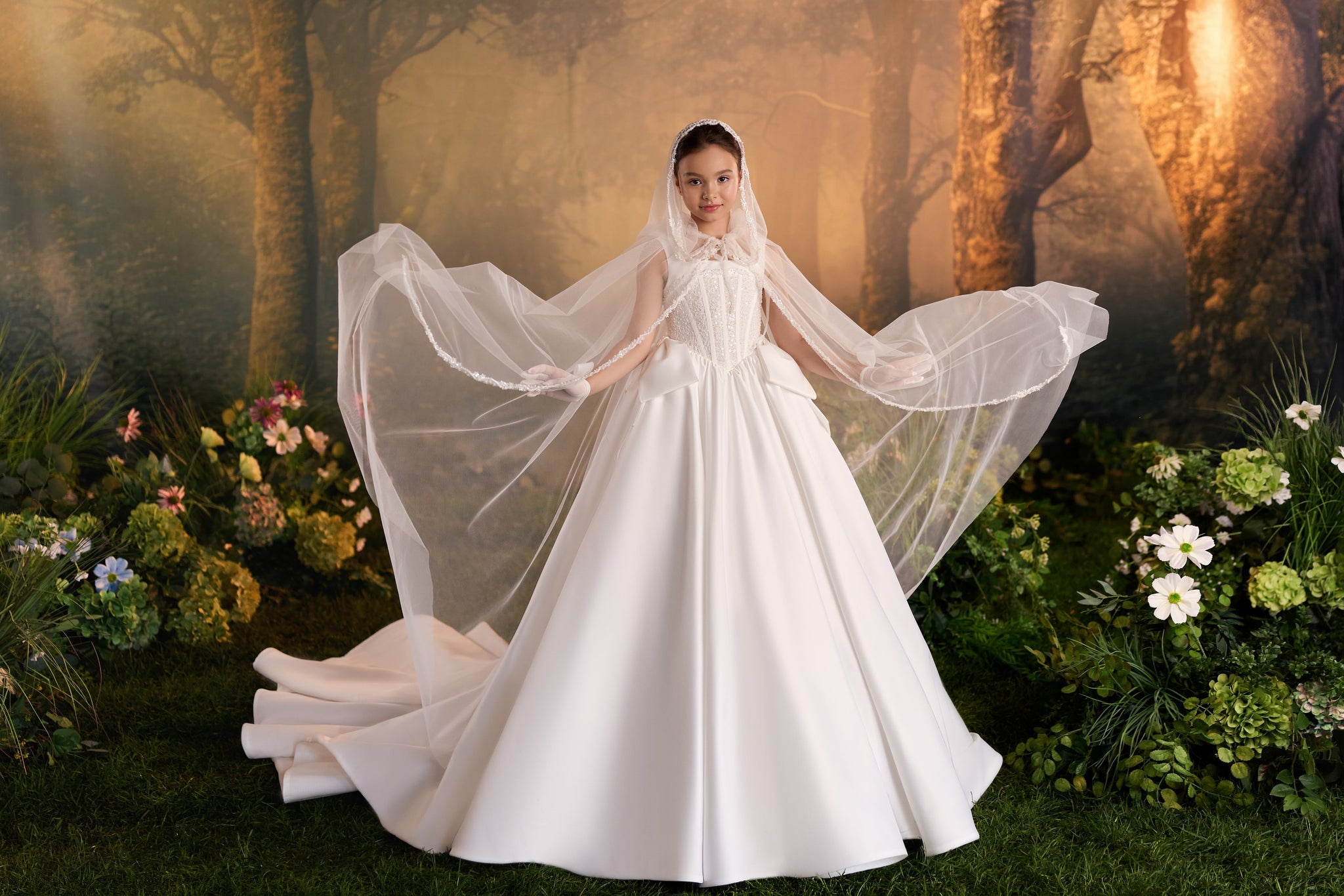 Girl wearing a white ballgown dress with a long cape in a forest setting | Girls Formal Dress