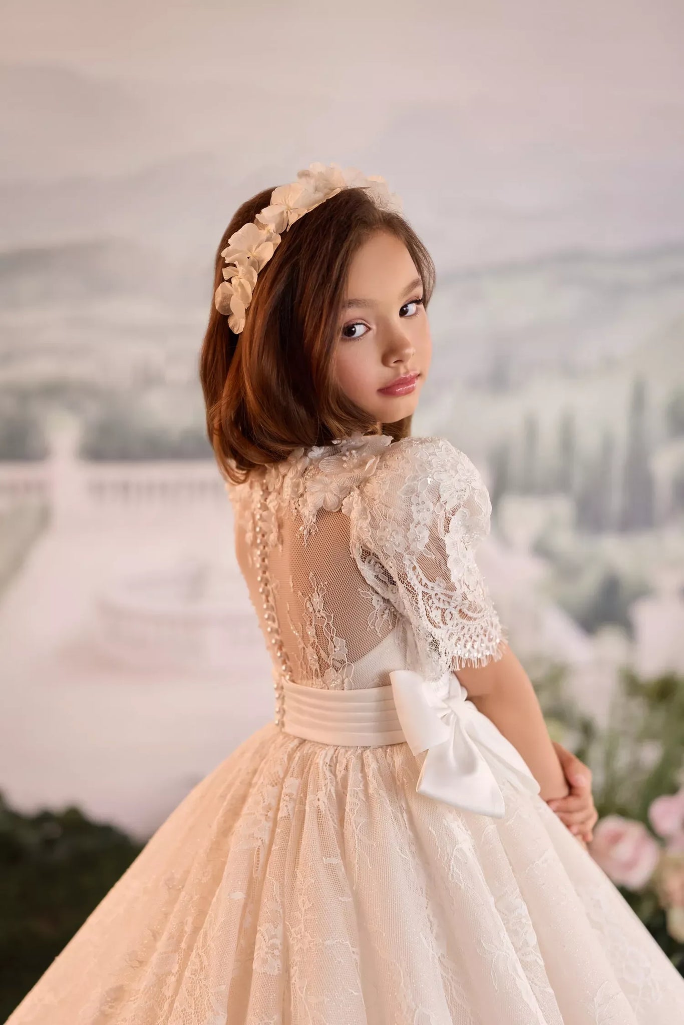 Girl wearing a white lace dress with a floral headband