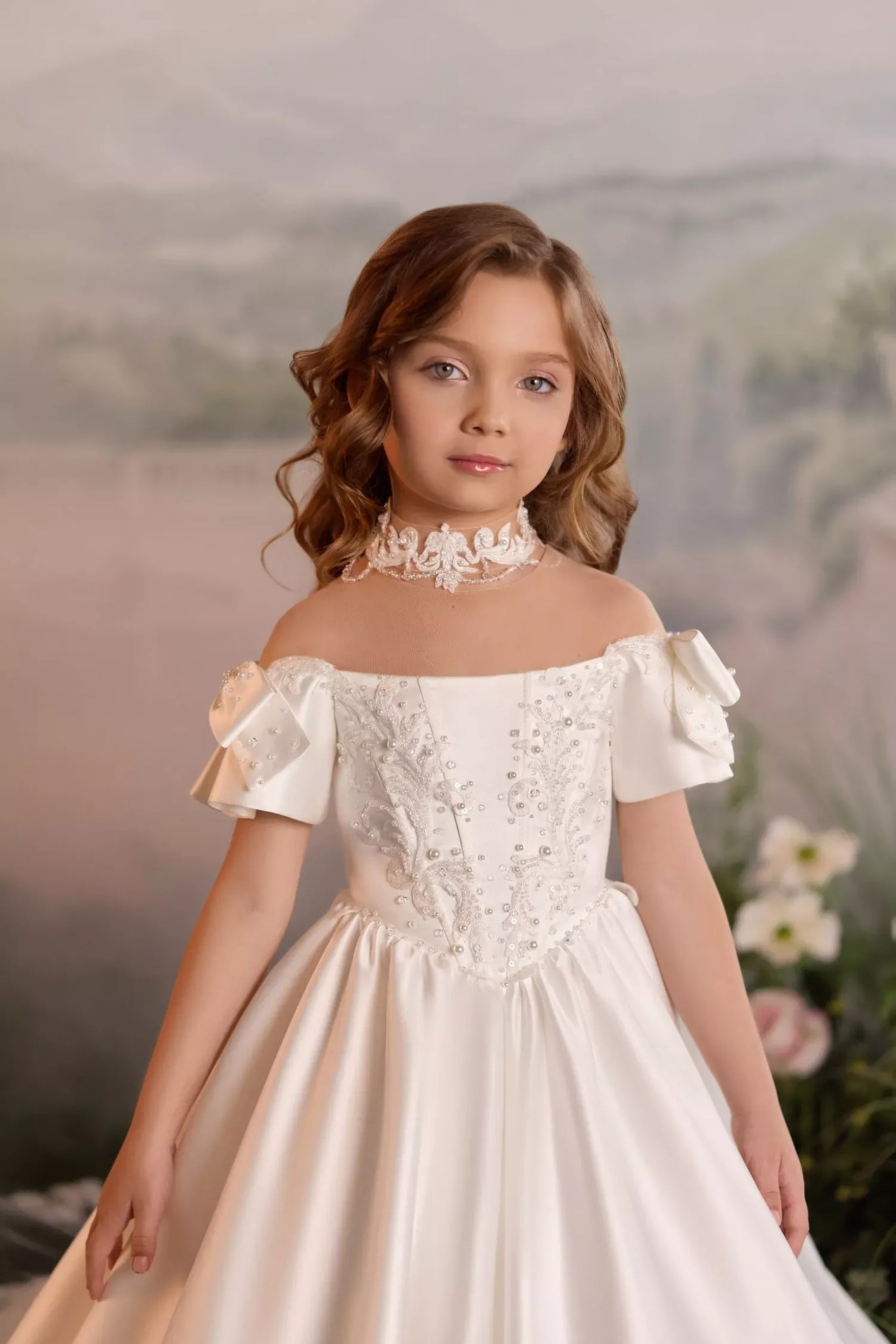 Girl wearing a white off shoulder dress with pearl and lace embellishments and a matching lace choker
