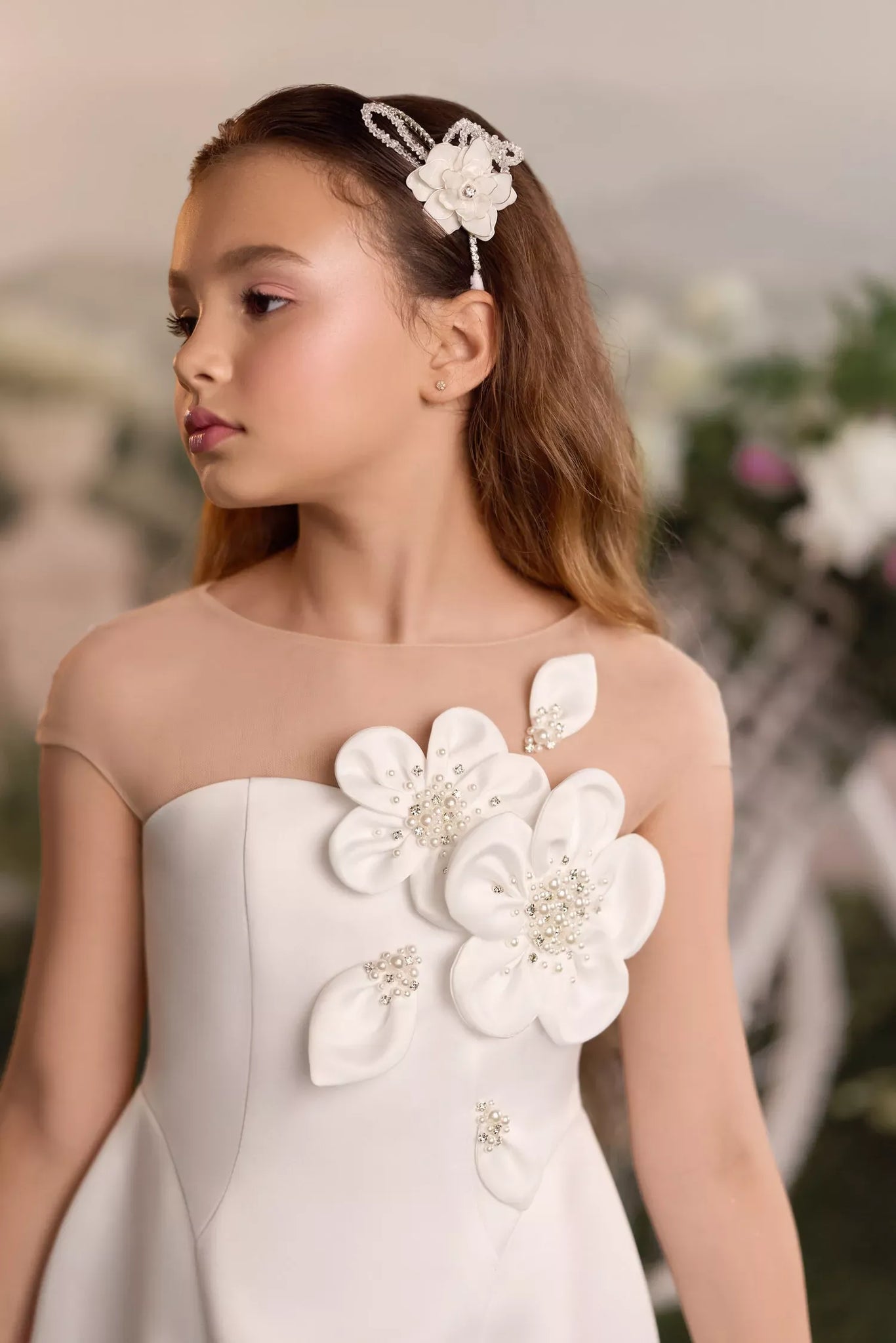 Girl wearing a white dress with floral embellishments and a matching hair accessory