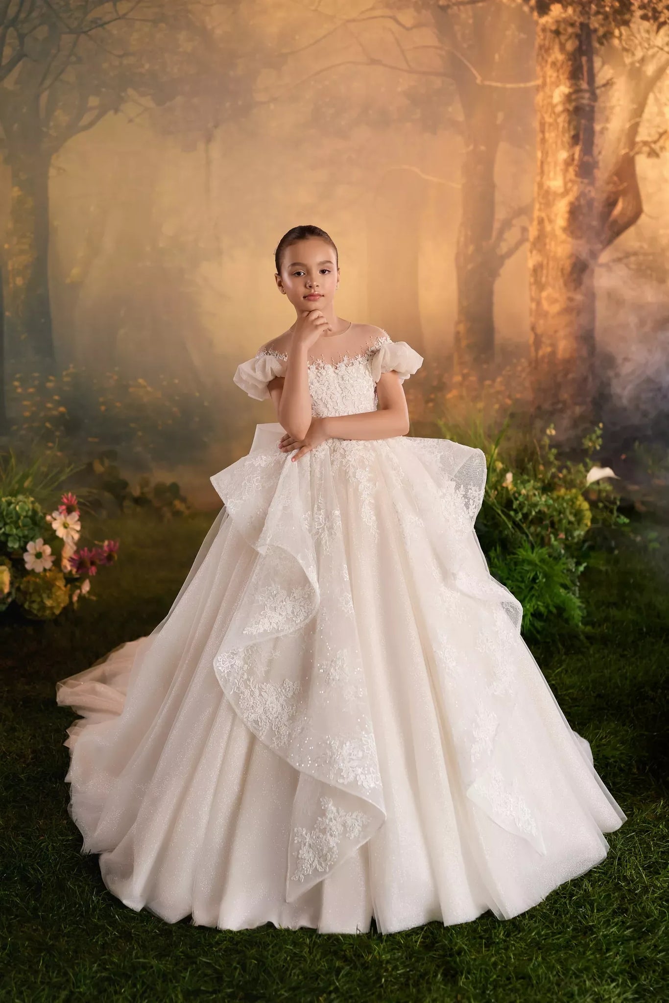 Girl wearing a white lace ball gown with off shoulder sleeves standing in a misty forest setting