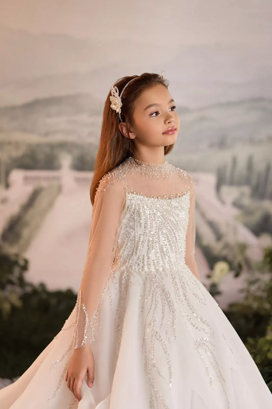 Girl wearing a white formal dress with beaded embellishments and a floral headband