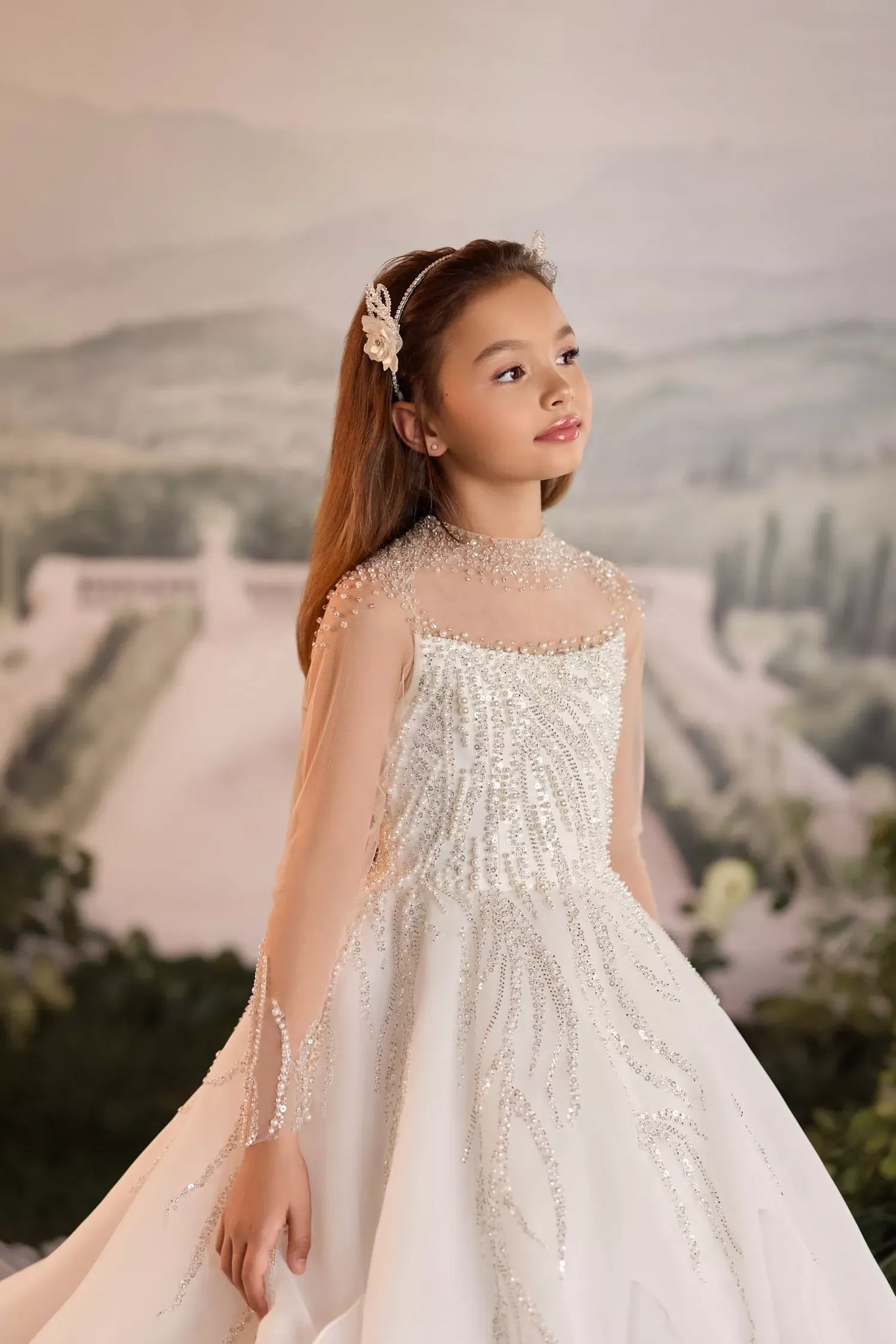 Girl wearing a white formal dress with beaded embellishments and a floral headband