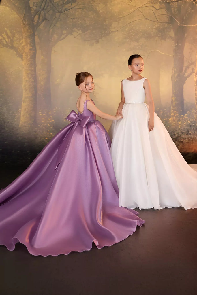 Two girls wearing formal floor length dresses in lilac and ivory standing in front of a forest backdrop | Girls Formal Dress