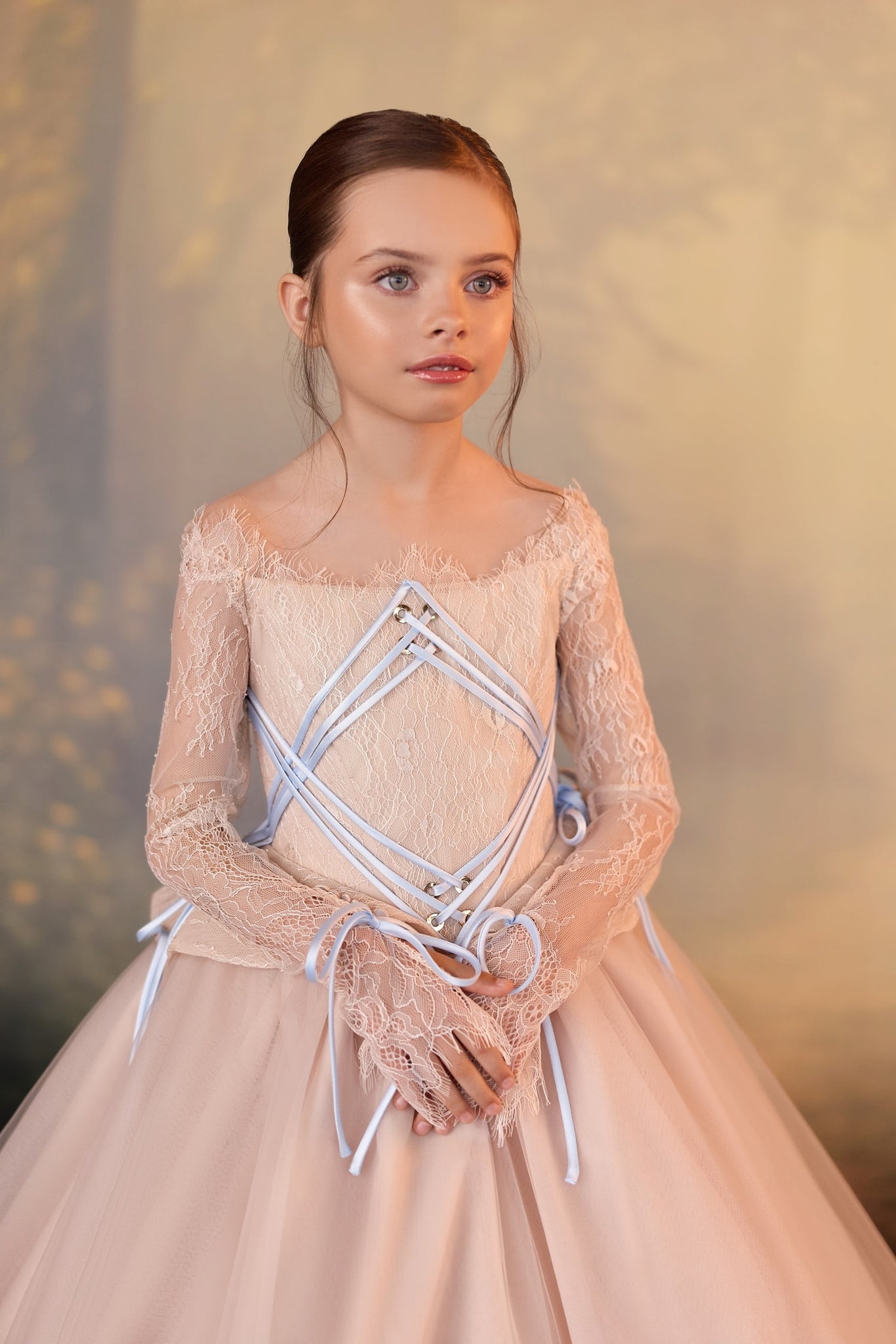 Girl wearing a long sleeved lace dress with corset style ribbon detailing | Girls Formal Dress