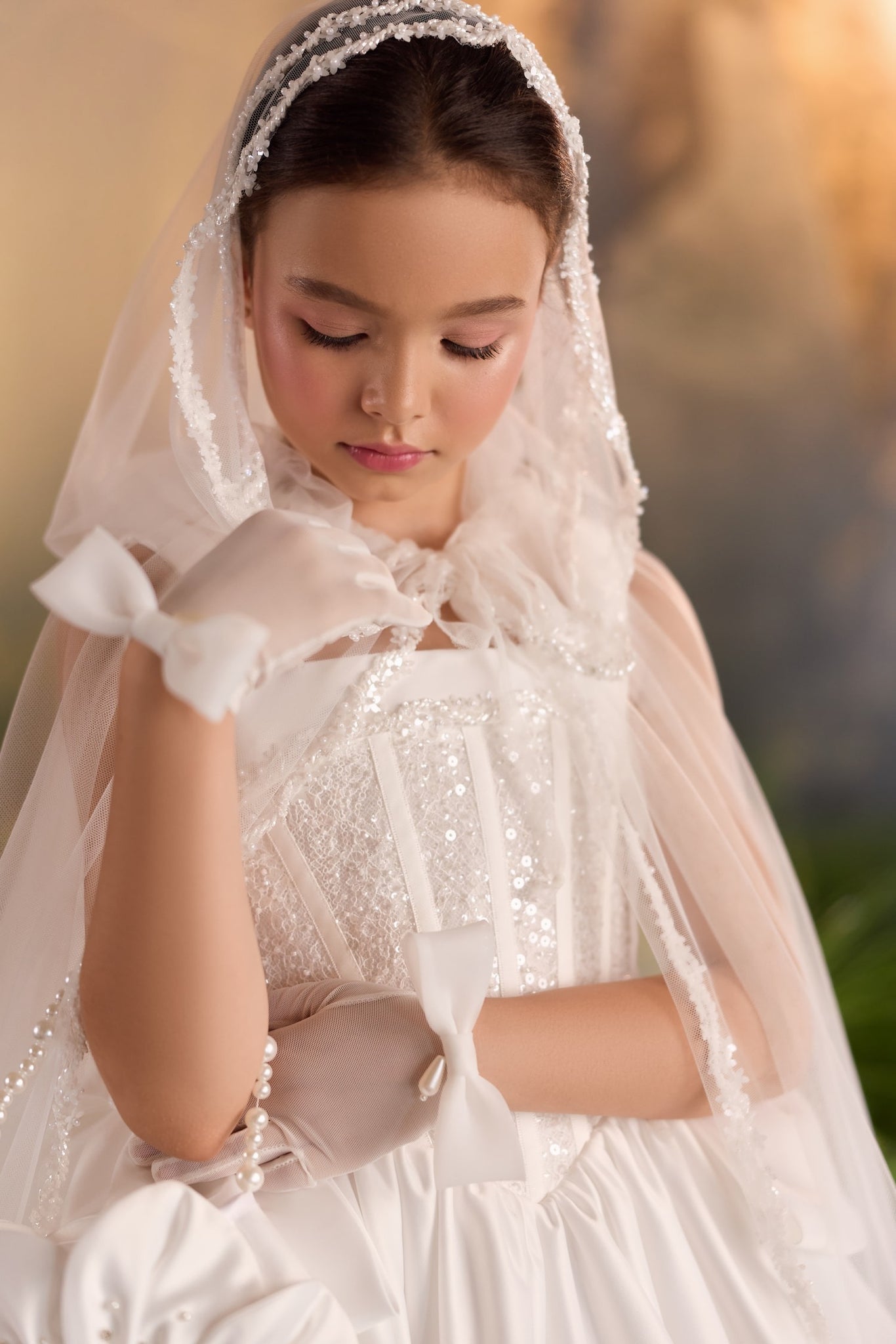 Girl wearing an embellished ball gown with a sheer cape and bow-accented gloves | Girls Formal Dress