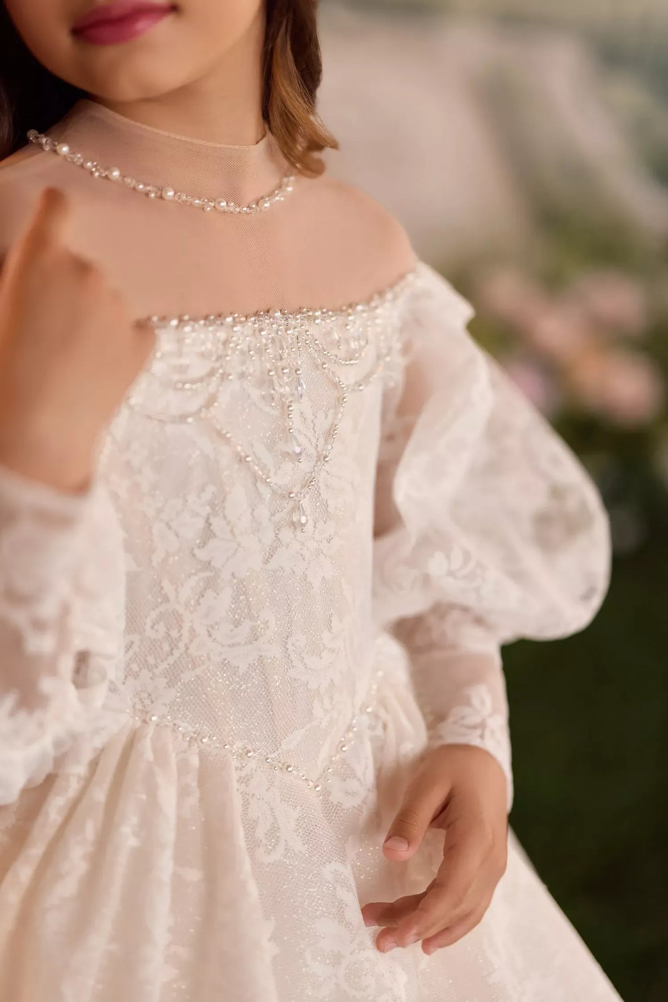 Girl wearing a white lace dress with pearl neckline and puff sleeves