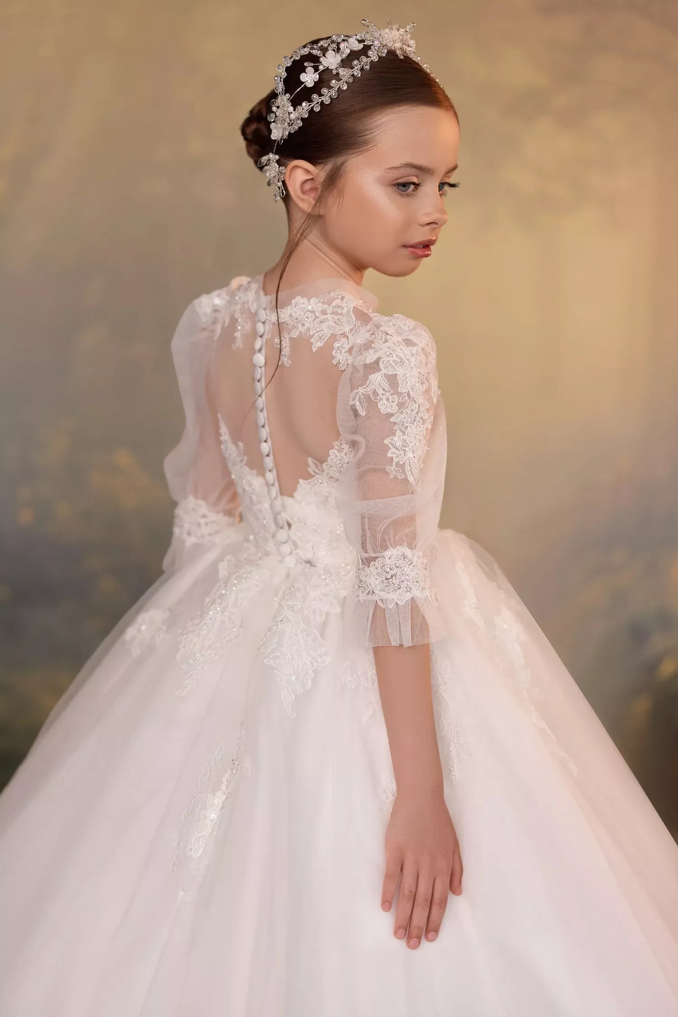 Girl wearing a lace ball gown with three-quarter puff sleeves and a floral headpiece | Girls Formal Dress