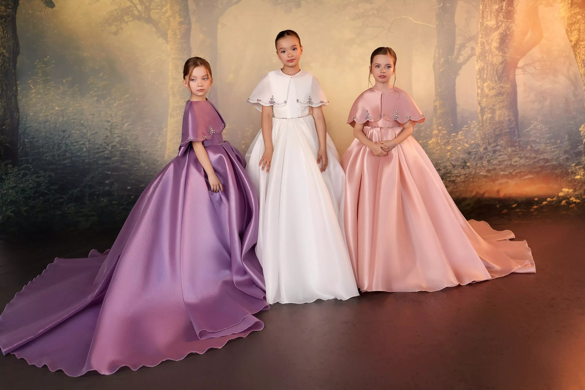 Three girls wearing floor-length dresses with coordinating embellished capelets | Girls Formal Dress