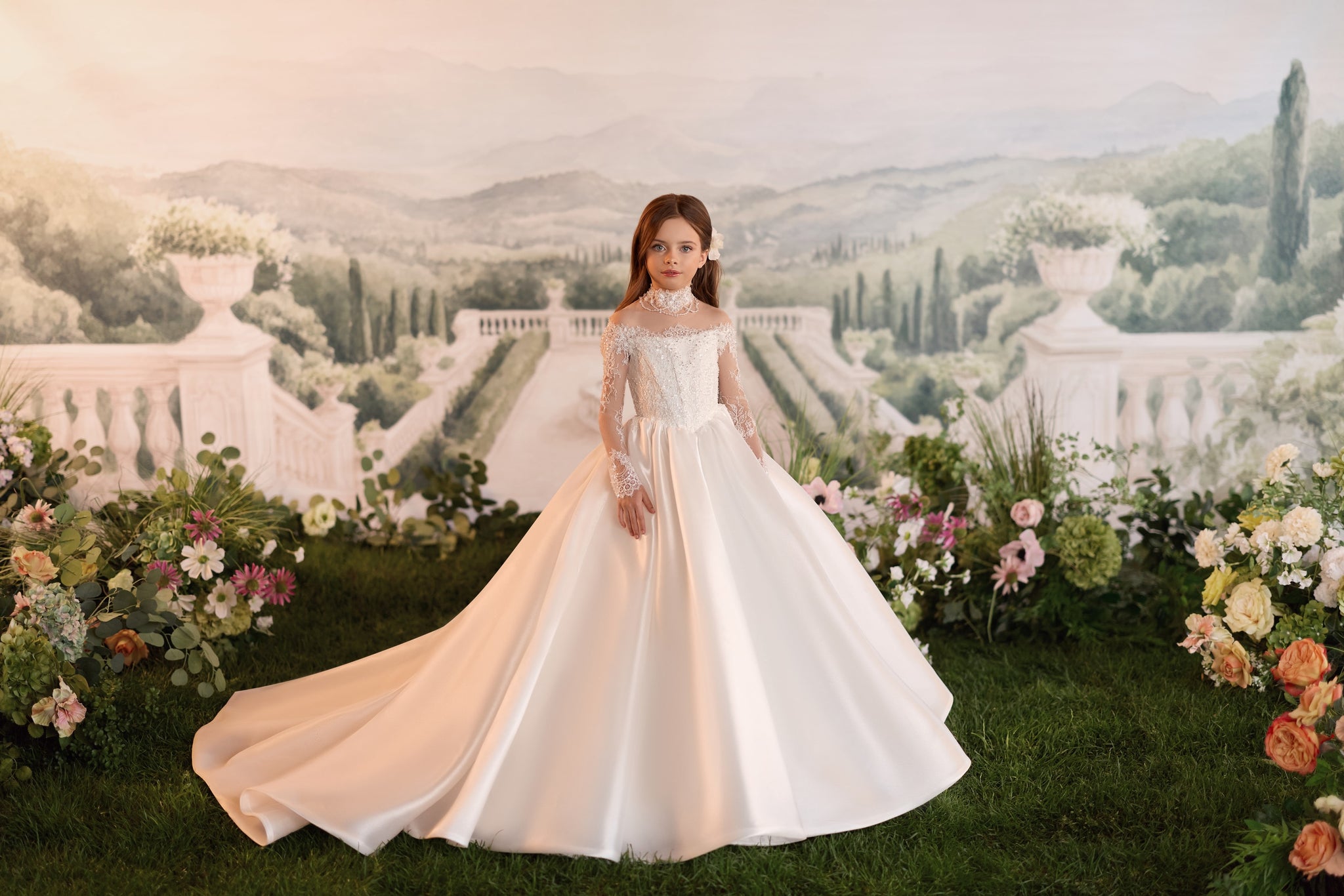 Girl wearing a white long sleeve lace ball gown standing in a garden setting
