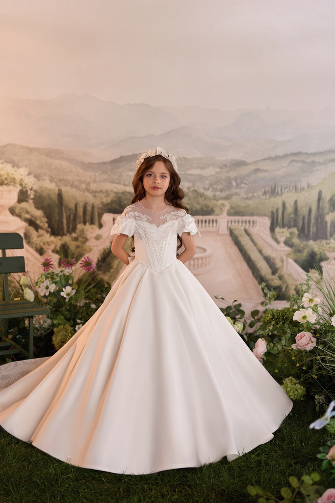 Girl wearing a white ball gown with lace details and a floral headband | Girls Formal Dress