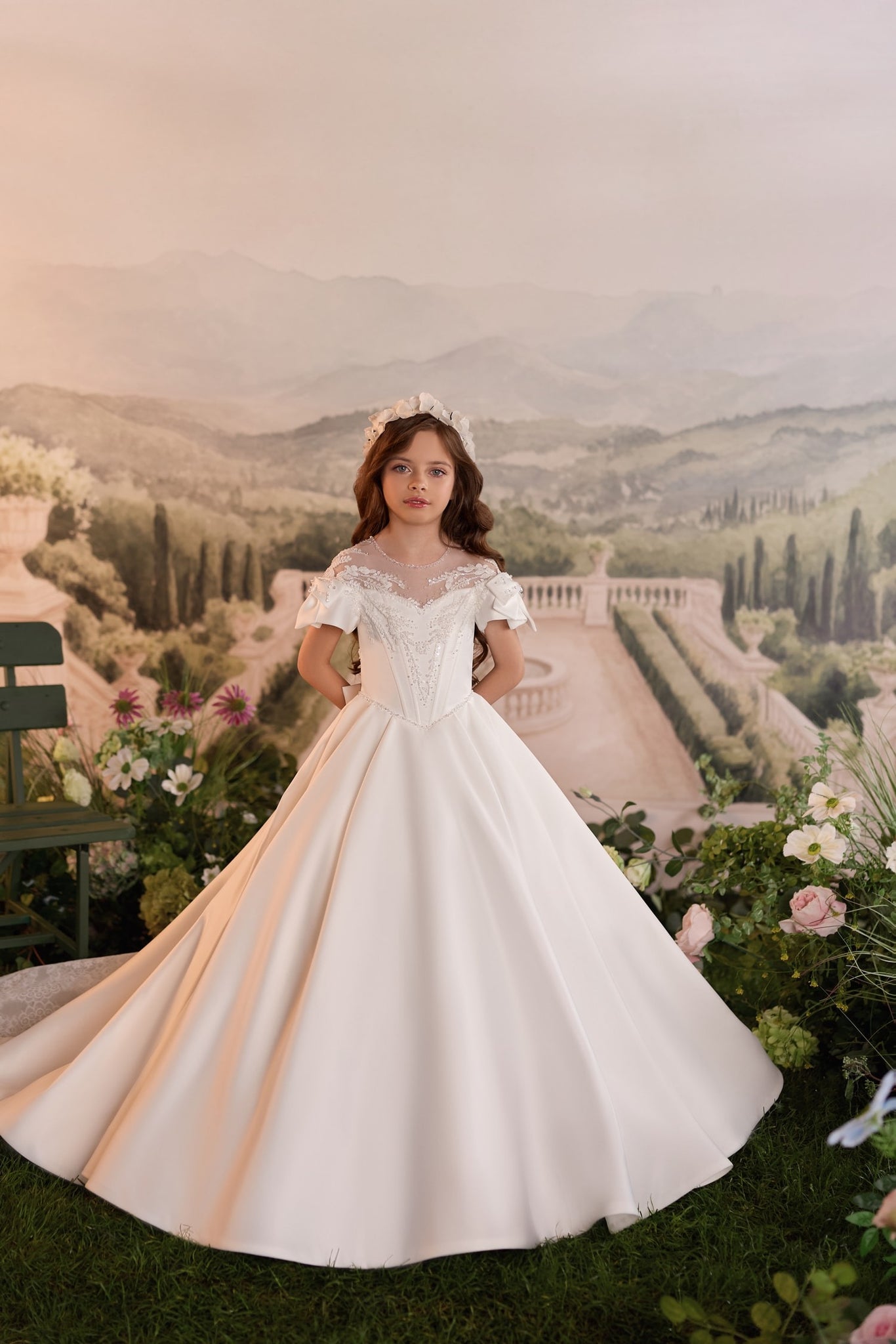 Girl wearing a white ball gown with lace details and a floral headband