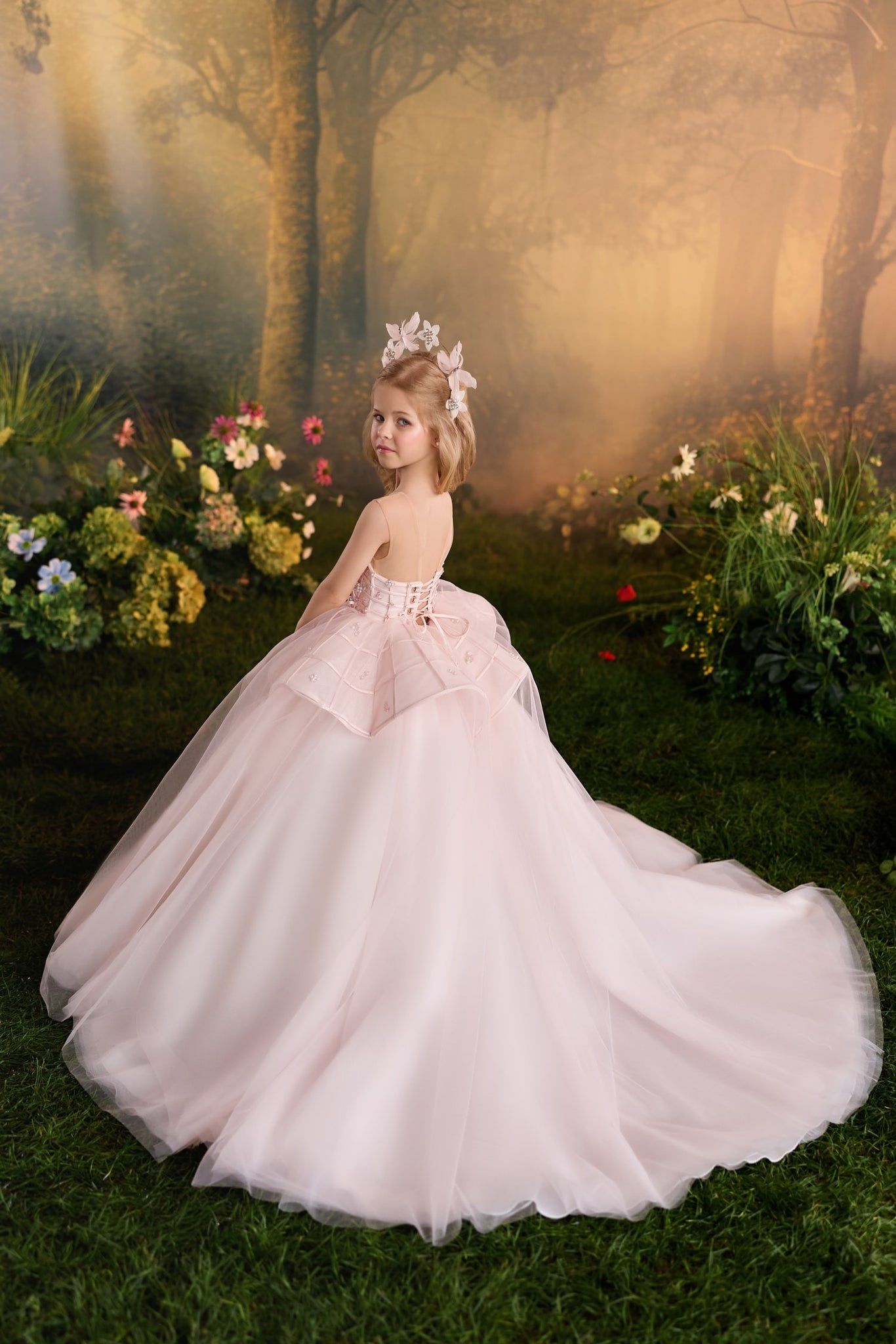 Girl wearing a pink ball gown with a floral headpiece in a garden setting