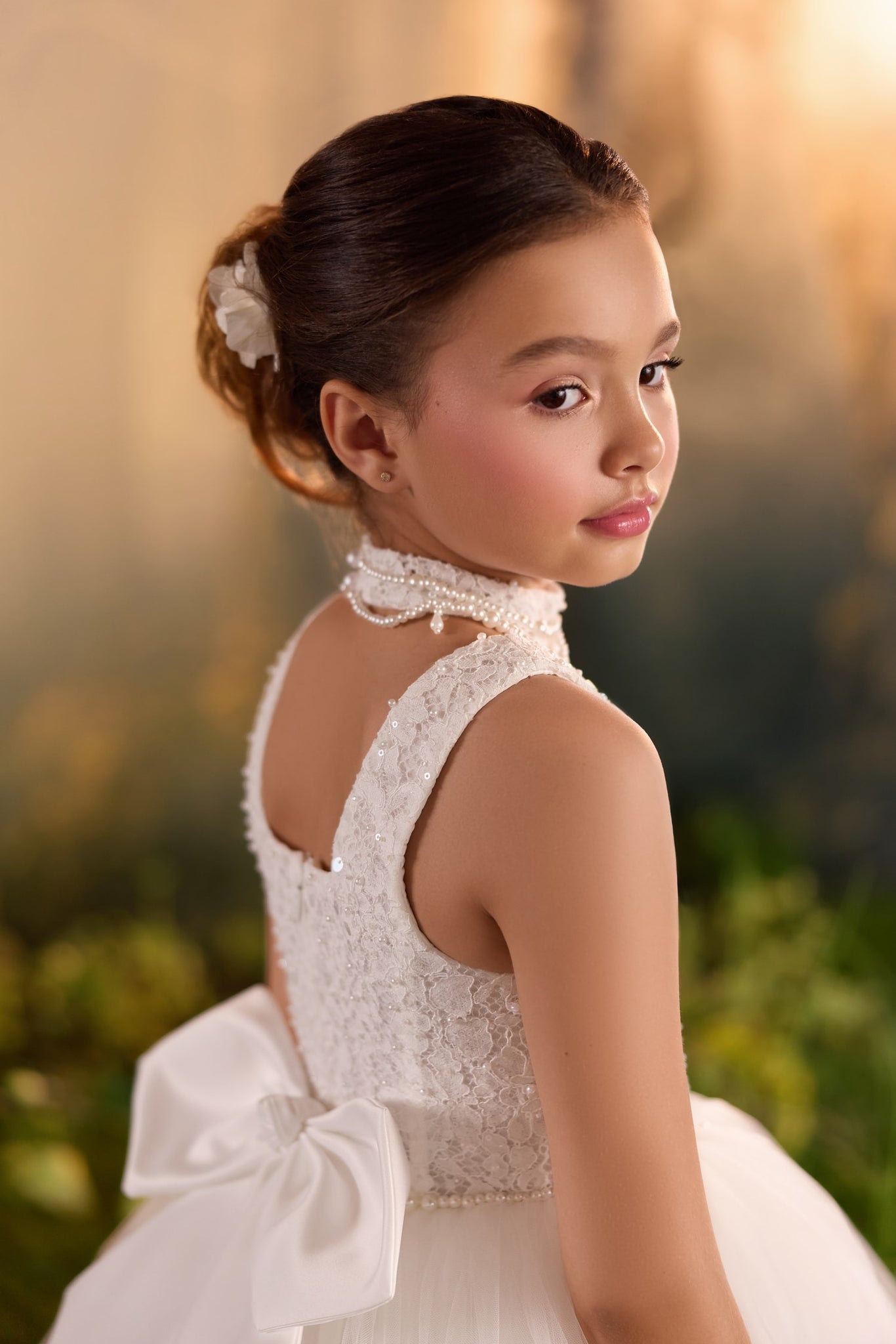 Girl wearing a white lace dress with a pearl collar and a large bow on the back | Girls Formal Dress
