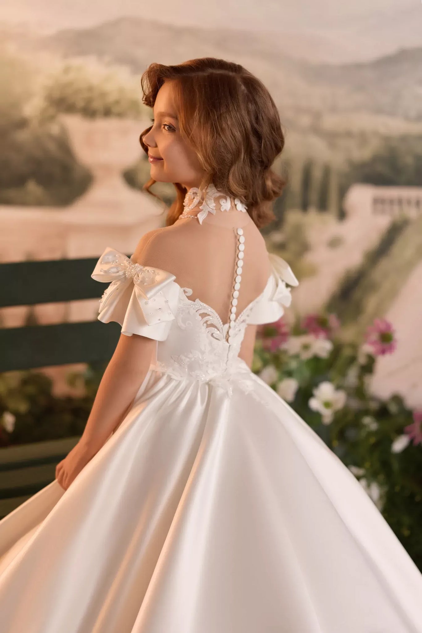 Girl wearing a white satin formal dress with off shoulder sleeves and button back detail