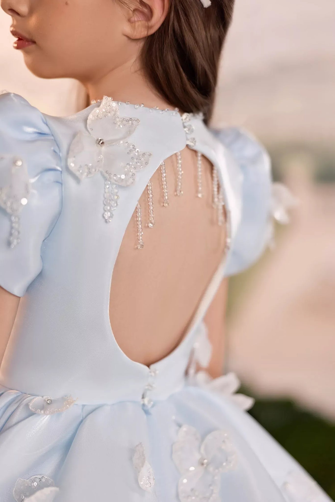Back view of a light blue dress with a cutout back and beaded floral embellishments