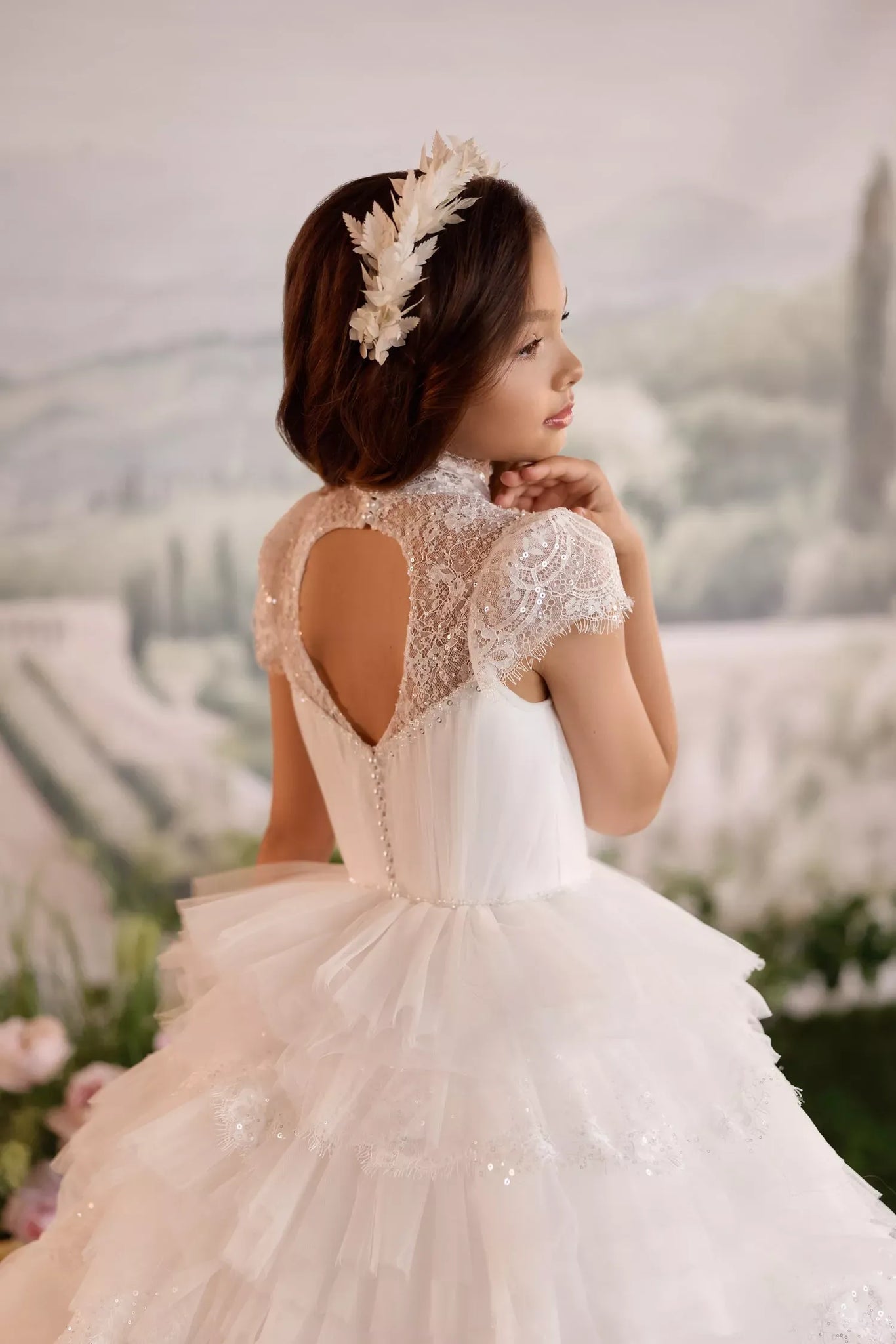 Girl wearing a white lace dress with a keyhole back and a floral headpiece