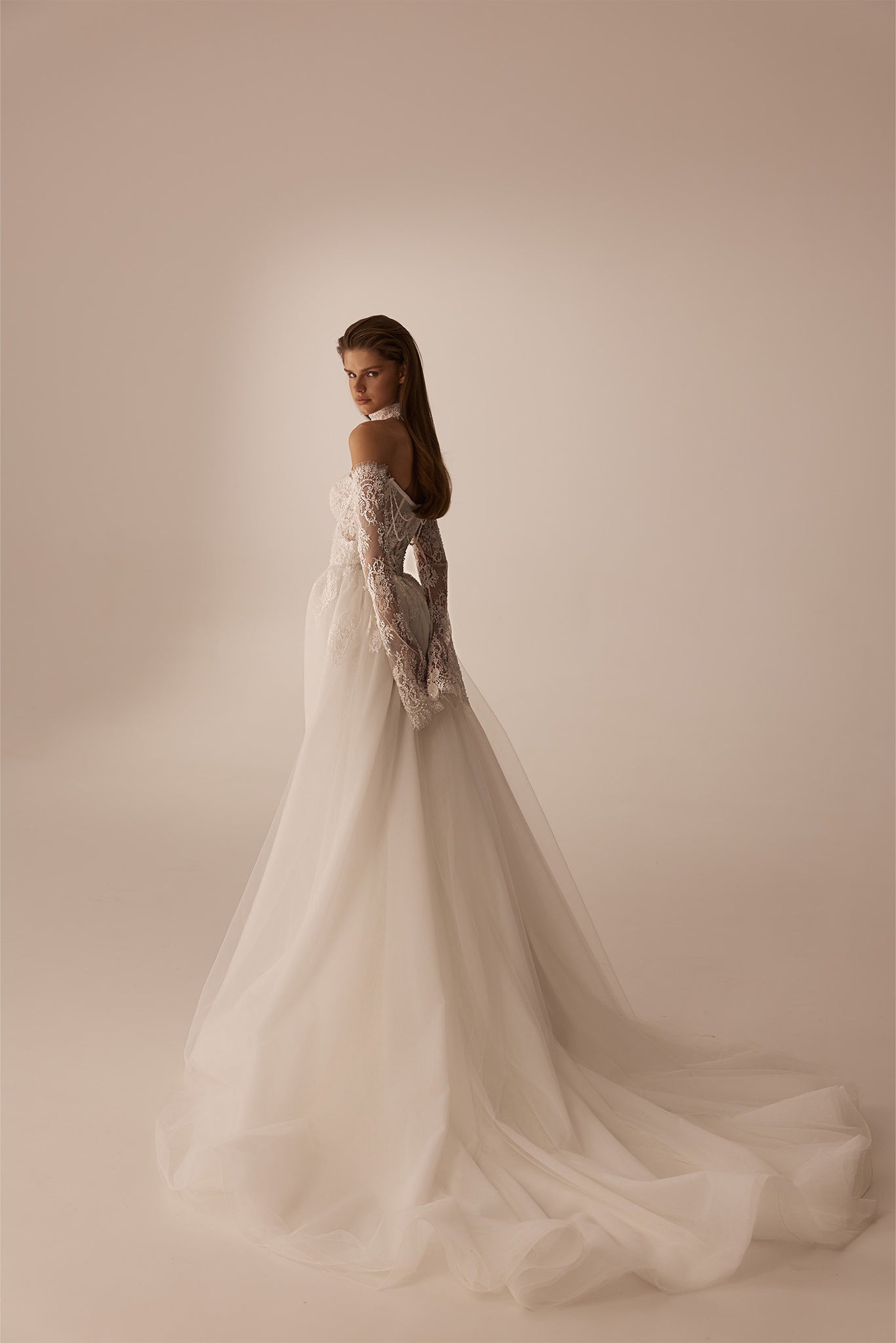 Model wearing an off the shoulder long sleeve lace wedding dress with a full tulle skirt