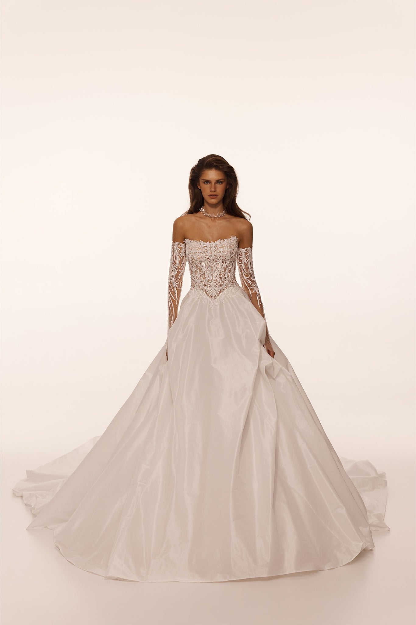 Model wearing an off the shoulder wedding dress with lace bodice and full skirt