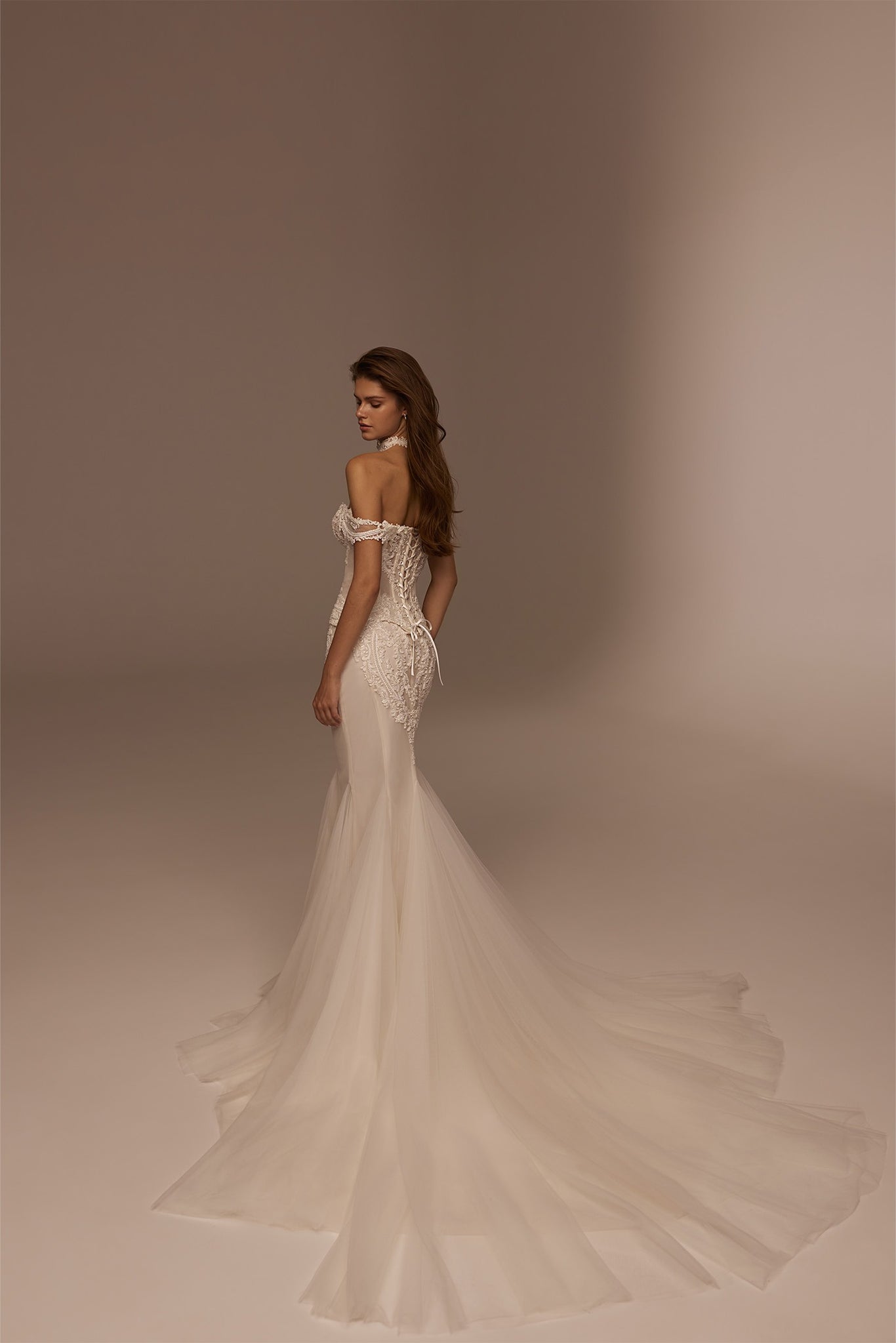Model wearing an off the shoulder lace corset wedding dress with a long tulle train