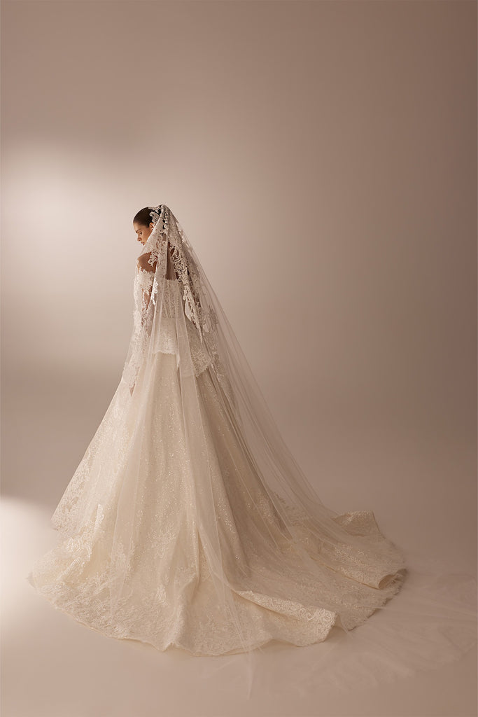 Bride wearing a white lace ballgown wedding dress with a long matching lace veil