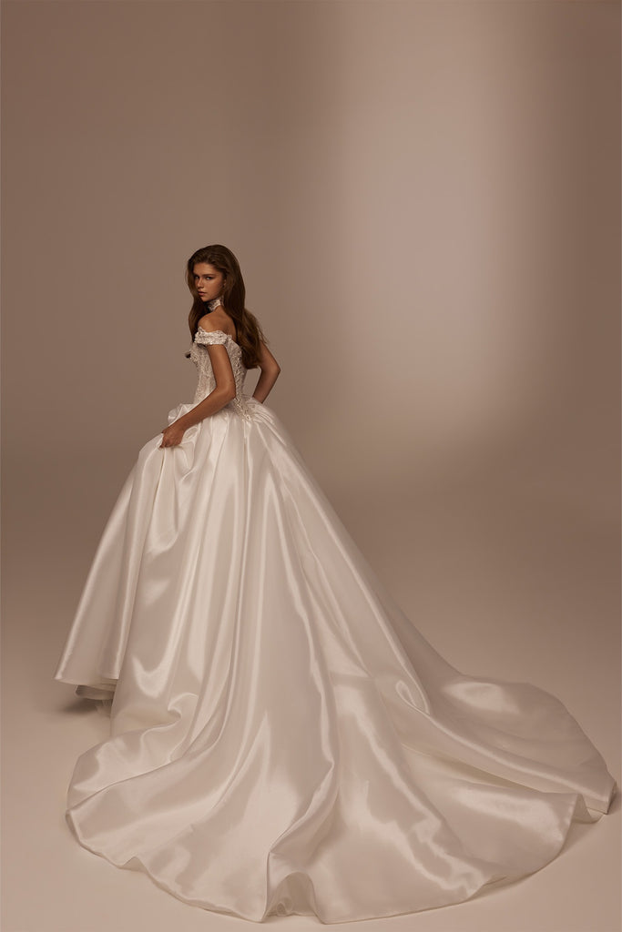 Woman wearing a white off the shoulder ballgown wedding dress with a long train
