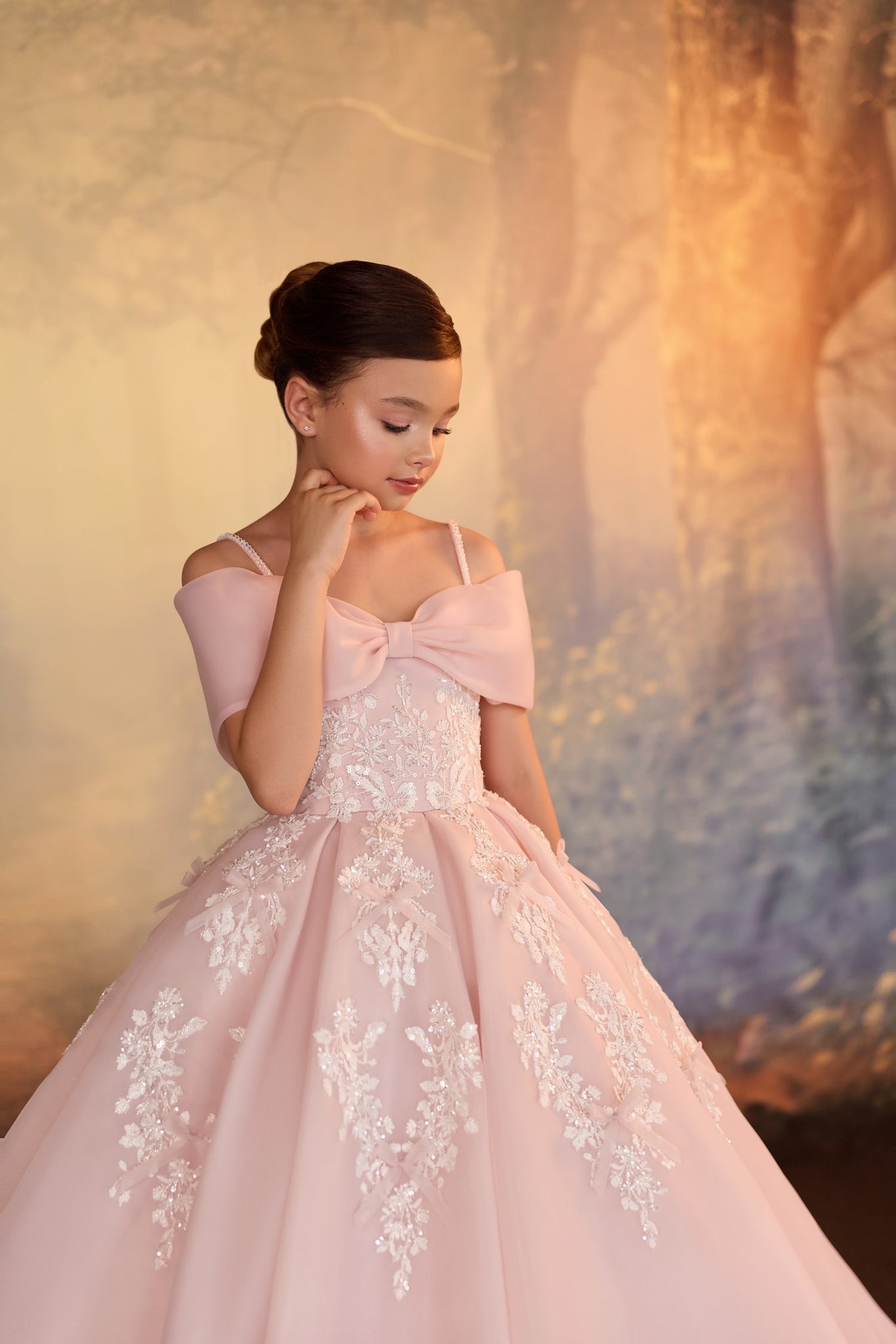 Girl wearing a pink off the shoulder ball gown with lace embroidery and a bow detail