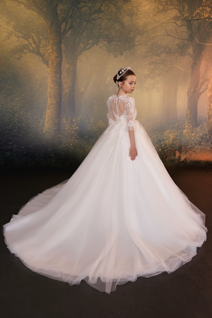 Girl wearing a white lace ball gown with a long train and a decorative headpiece | Girls Formal Dress