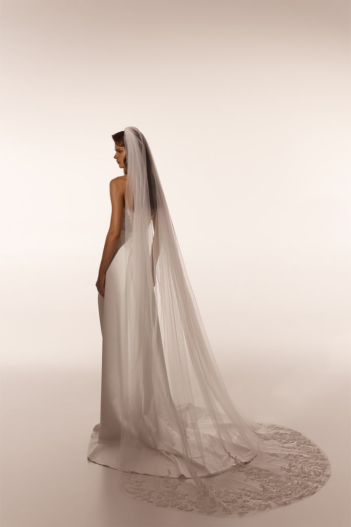 Bride wearing a long white wedding dress and a floor length veil with lace trim